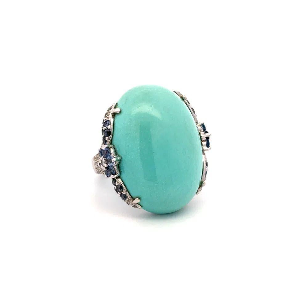 Simply Beautiful! Elegant and Finely detailed Persian Turquoise, Sapphire and Diamond Platinum Vintage Cocktail Ring. Centering a securely nestled Hand set 12 Carat Oval Cabochon Persian Turquoise. Accented by Sapphires, weighing approx. 1.27tcw and