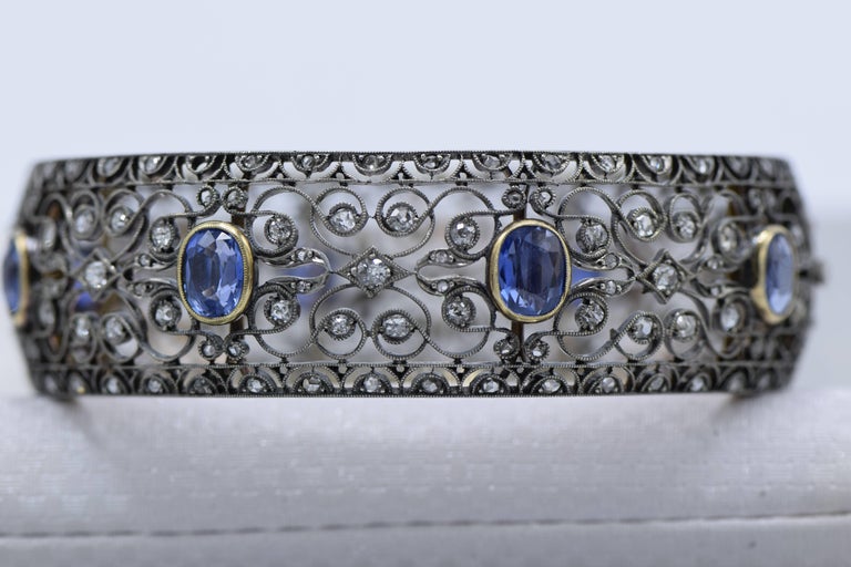 The wide hinged hoop pierced throughout with scroll and scallop motifs, decorated with eight oval sapphires weighing approximately 12.00 carats, and old-cut diamonds weighing approximately 7.00 carats, the gallery engraved with foliate details,