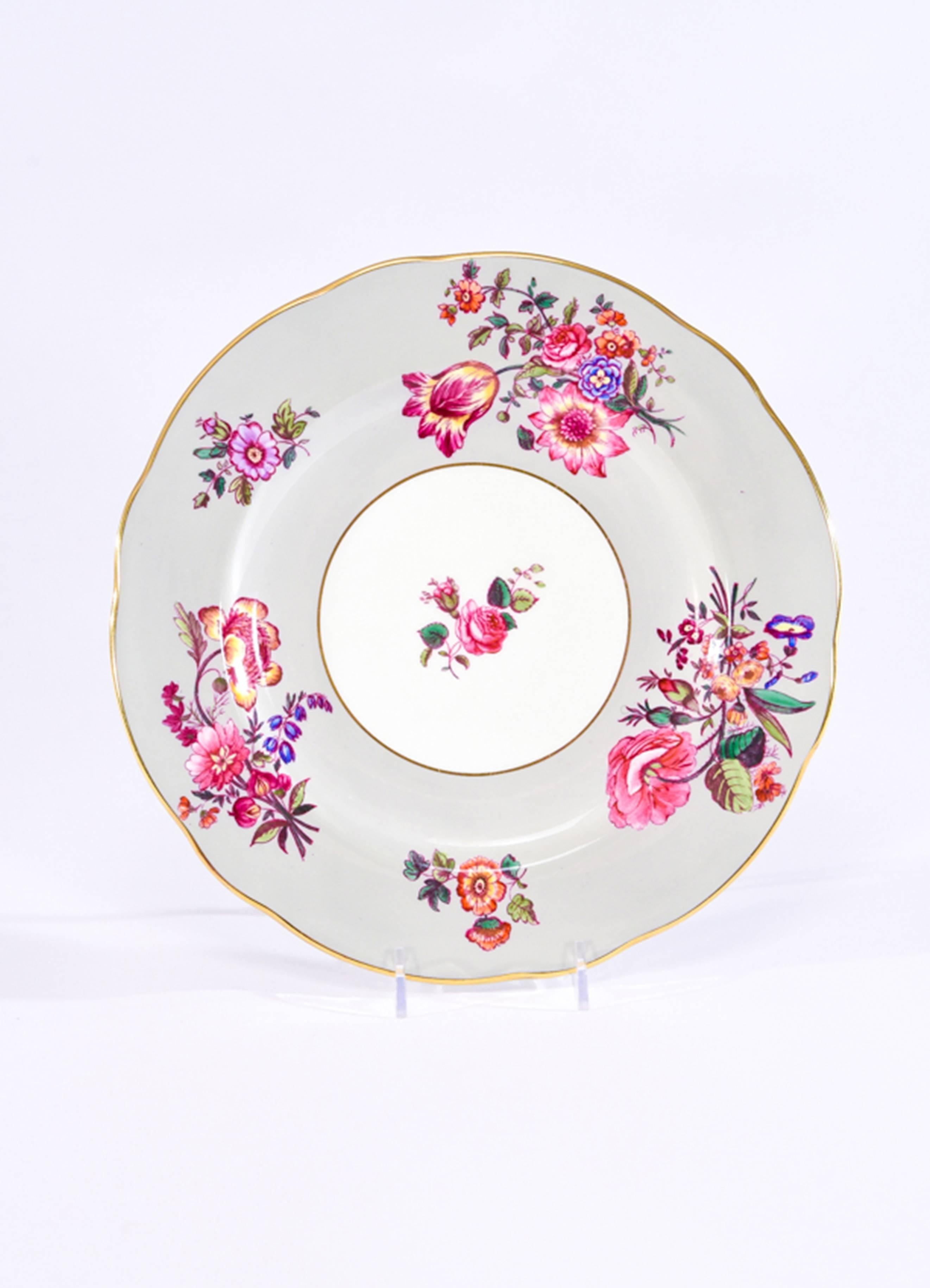 This set of 12 Coalport dinner plates feature an unusual color combination of a soft gray border decorated with a vibrant palette of brightly painted flowers. There are various combinations of flower arrangements encircling the border and the