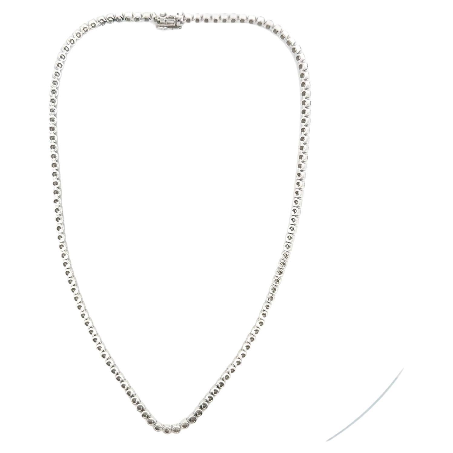 Modern diamond tennis necklace crafted in 14 karat white gold. The necklace features 121 round brilliant cut diamonds weighing approximately 12.0 carat total weight. The diamonds are graded H-I color and SI clarity. The necklace measures 16 inches