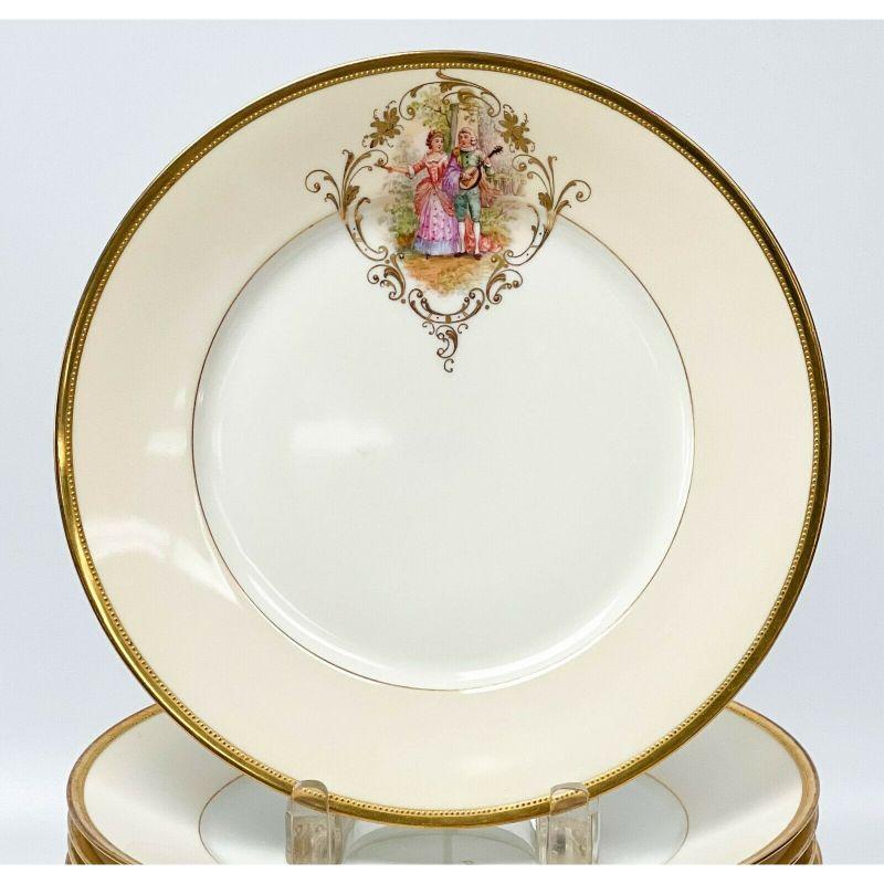 12 Dresden Ambrosius Lamm hand painted porcelain dinner plates, circa 1920. A white ground with cream yellow edge, gilt to the center edge and to the rim. Each with hand painted figural scenes framed by raised gilt foliate decoration. Beaded border