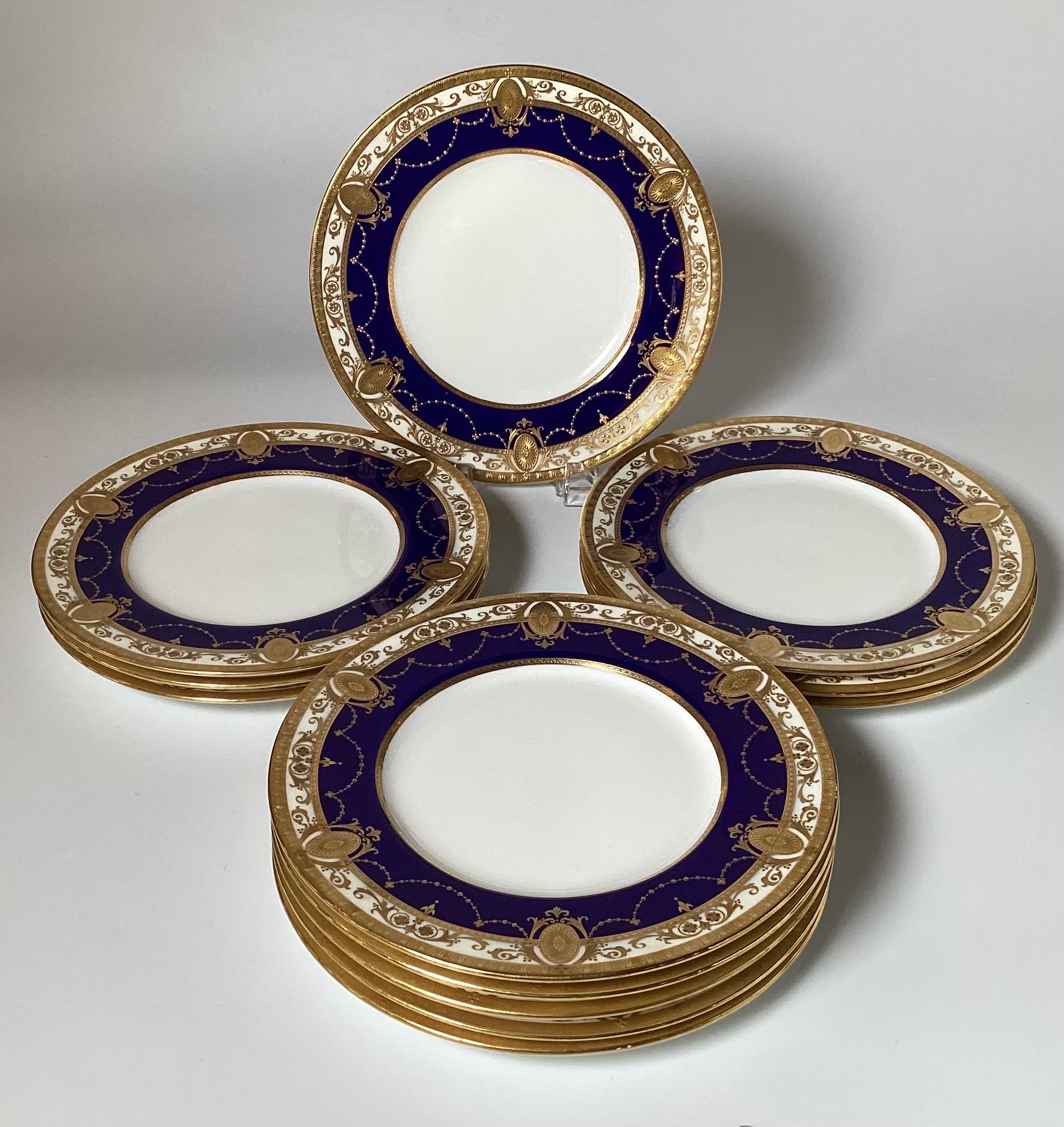 A set of 12 opulent and regal cobalt bordered dinner service plated by Minton England.  The deep blue borders with raised god overlay decoration with medallion and swag pattern.  10.25 inches in Diameter