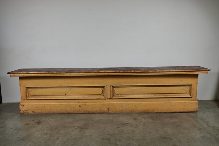 Architectural late 19th century general store counter. Layers of original mustard paint surface and red stained top. Superb architectural detailing and carved top with rolled edge. One side appears to have been up against something and does not have