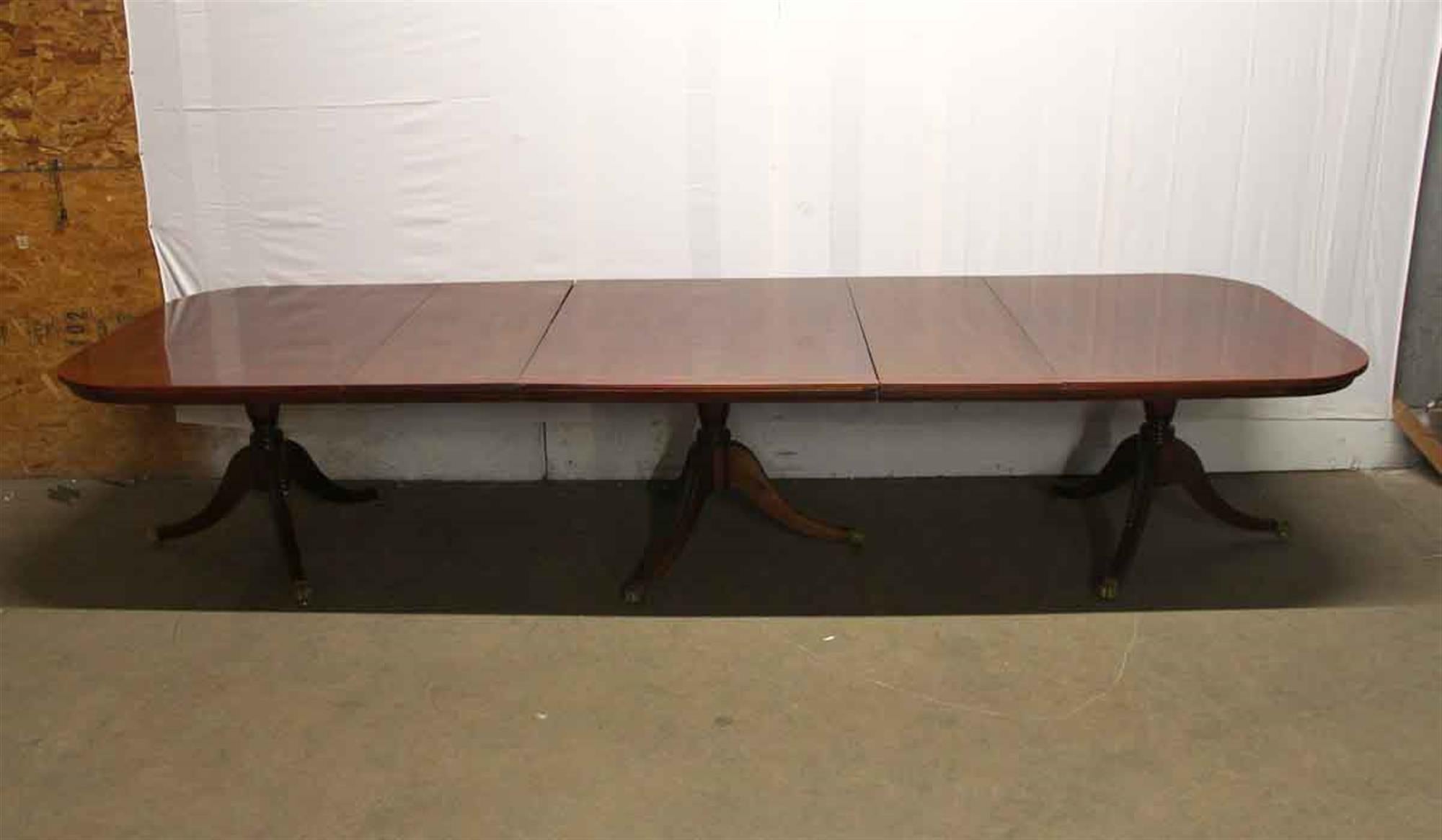 Mahogany Duncan Phyfe style dining room table with extensions and brass claw feet. Supreme quality carved mahogany with an inlaid border. One large leaf and two smaller leafs. One of the smaller leafs is discolored and will need refinishing. This