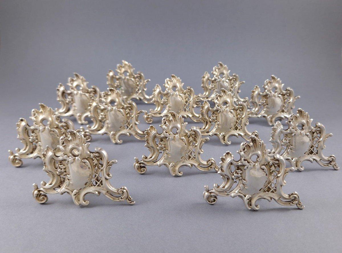 Set of 12 Sterling Silver Place Card Holders with openwork decoration, rocaille, foliage and flowers 
Minerva hallmark 1st title for 950/1000 purity silver
Height: 5.5 cm 
Length: 7.5 cm 
Weight: 594 grams