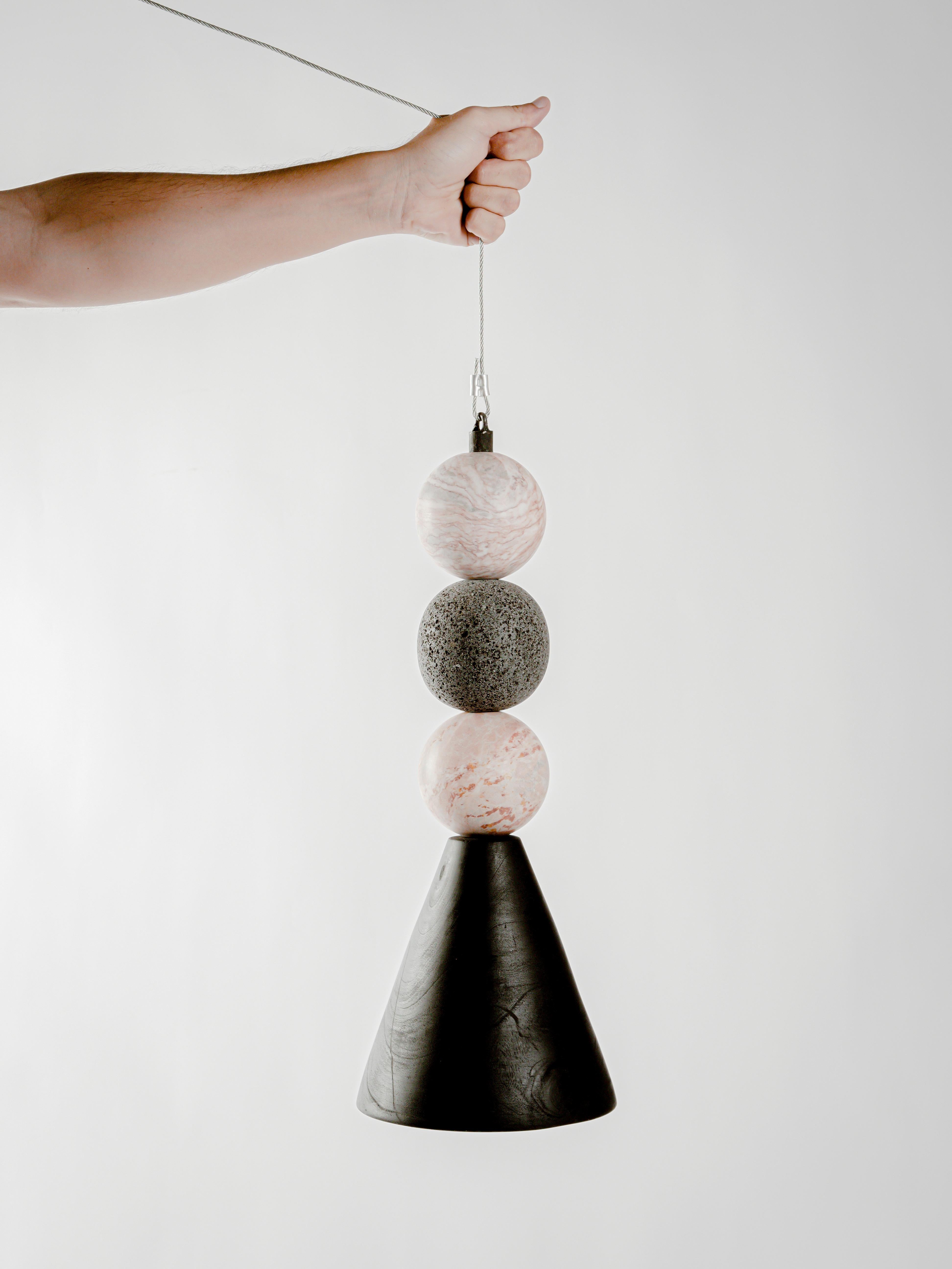 12 Lamp by Daniel Orozco
Dimensions: D 20 x H 50 cm.
Materials: Wood, Volcanic Stone.

Hanging lamp with conical burn wooden base, 2 pink marble spheres and 1 volcanic stone.

All our lamps can be wired according to each country. If sold to the USA