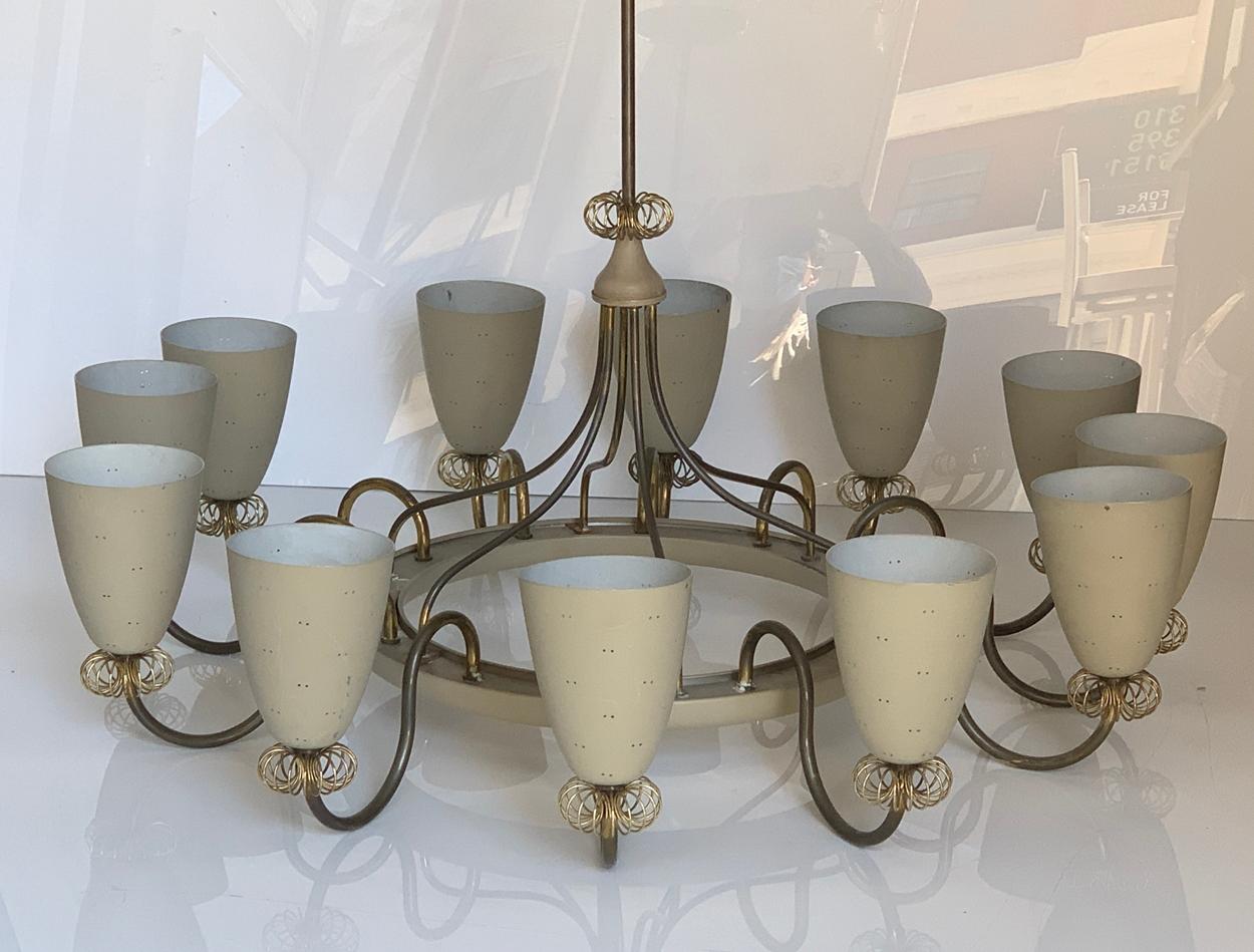 Canadian, 1950s. 

 A painted aluminum 12 light chandelier designed by Paavo Tynell for Lightolier Canada, having central gray enameled ring or circulet issuing twelve brass scrolling arms with coiled wire decoration terminating in twelve upturned