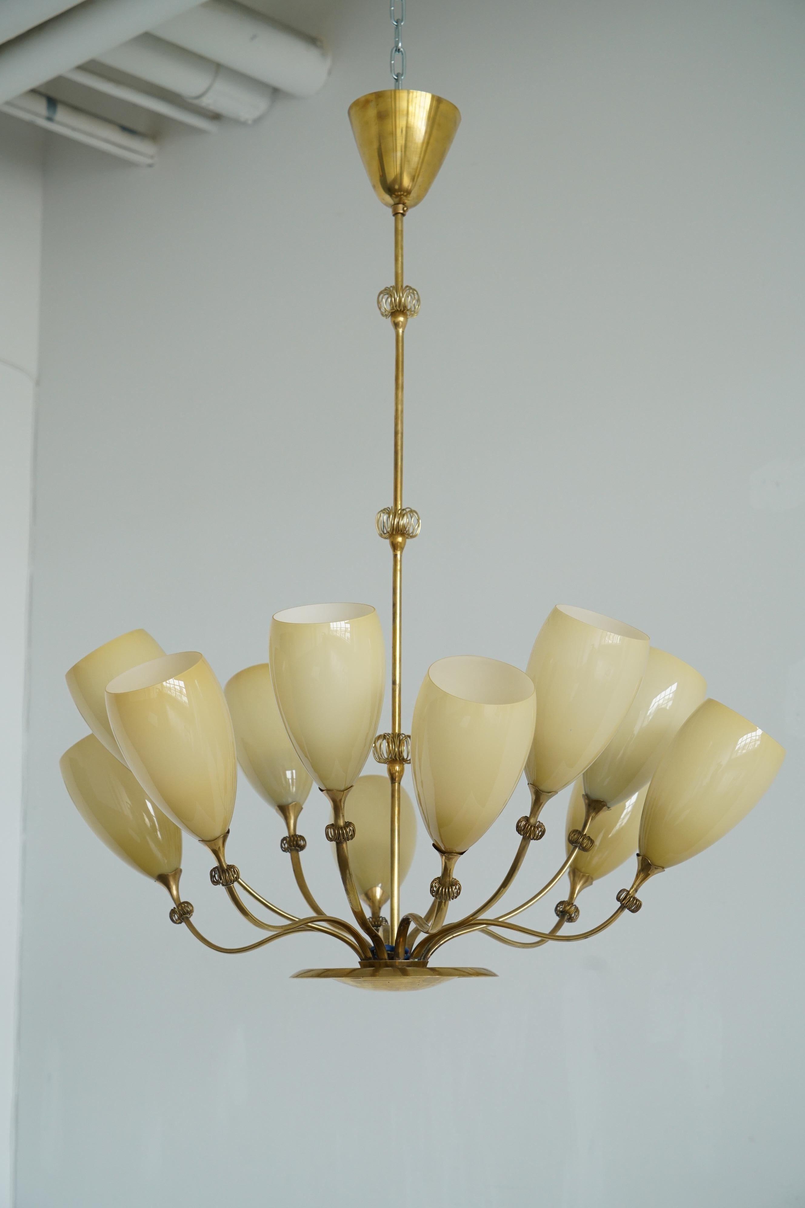 Grand lustre à 12 lumières de Paavo Tynell pour Idman. Finlande, Circa 1950th.
Abat-jour en laiton et verre opalin avec décoration en fil de laiton.
Exemple similaire sur le dessin d'archive Idman n° 3264.
Le lustre doit être recâblé avant d'être