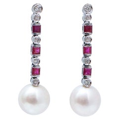 Orecchini in oro bianco con perle da 12 mm, rubini e diamanti.