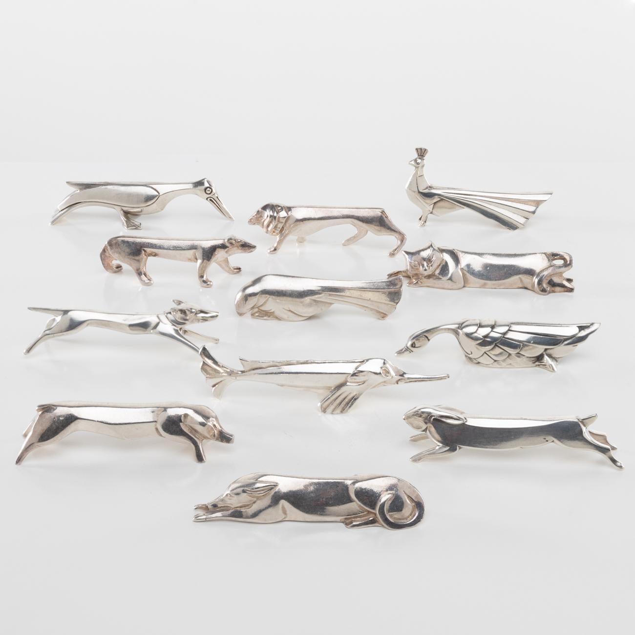 This iconic series of knife-rests was designed by Swiss cubist sculptor Edouard Marcel Sandoz for the well-known Parisian silversmith Christofle. 
It represents twelve animals: a lying cat, a lying dog, a pig, a bear, a budgerigar, a lion, a hare,