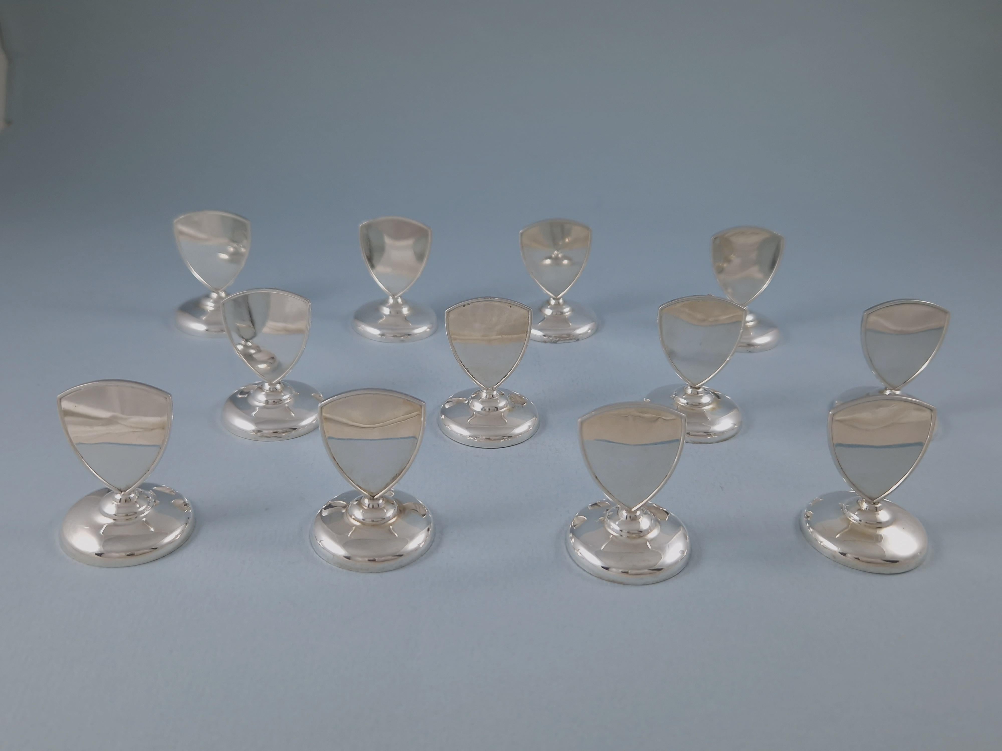 Nice set of twelve Solid Silver place card holders in the shape of a crest 

800 silver hallmark 

Height: 2.5 cm 
Weight: 180 grams
Good condition.