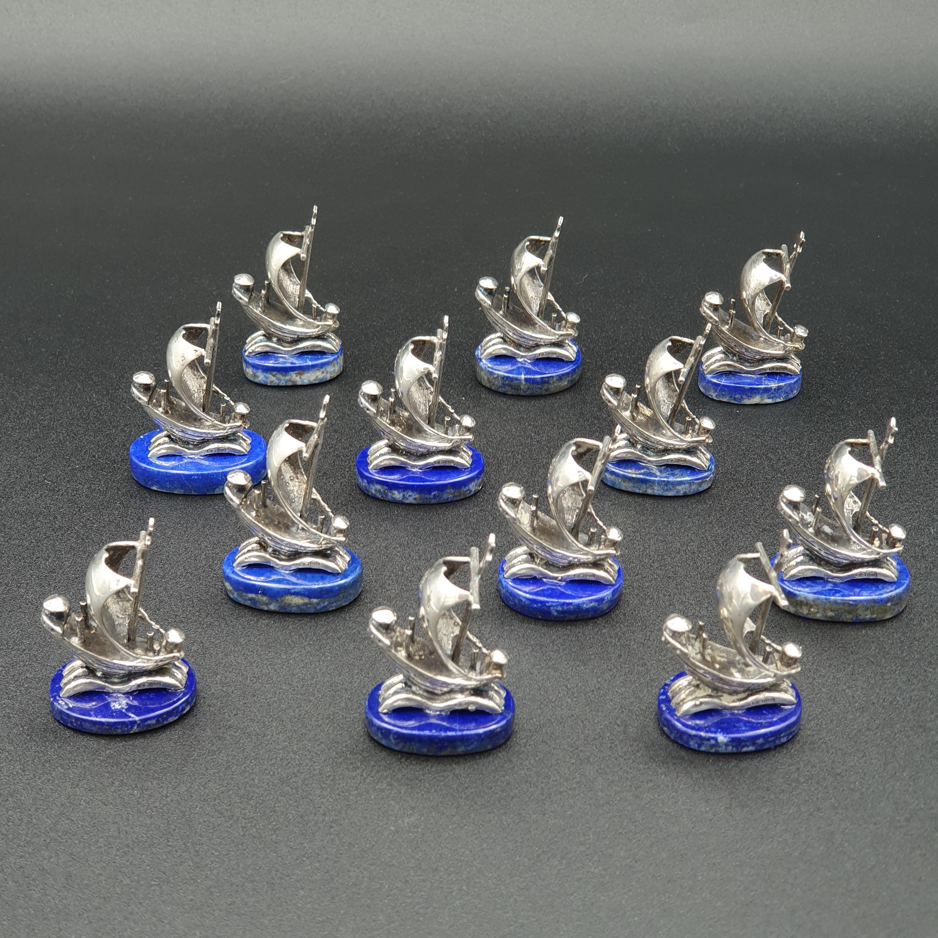 12 place cards holders in solid silver, in the shape of a sailing boat 

The base in lapis lazuli 

Silver hallmark 800 

Measures: Height: 4.3 cm 
Length: 3 cm

Good condition.