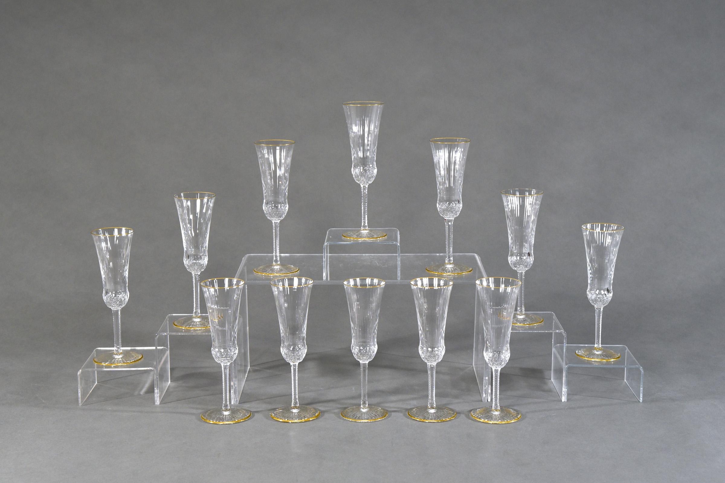 These are the classic, iconic champagne flutes made by St. Louis in a perfect set of 12. Hand blown crystal with optic rib cutting, zipper cut stem and star cut base. The subtle ribbed design is highlighted in gold and these are in excellent