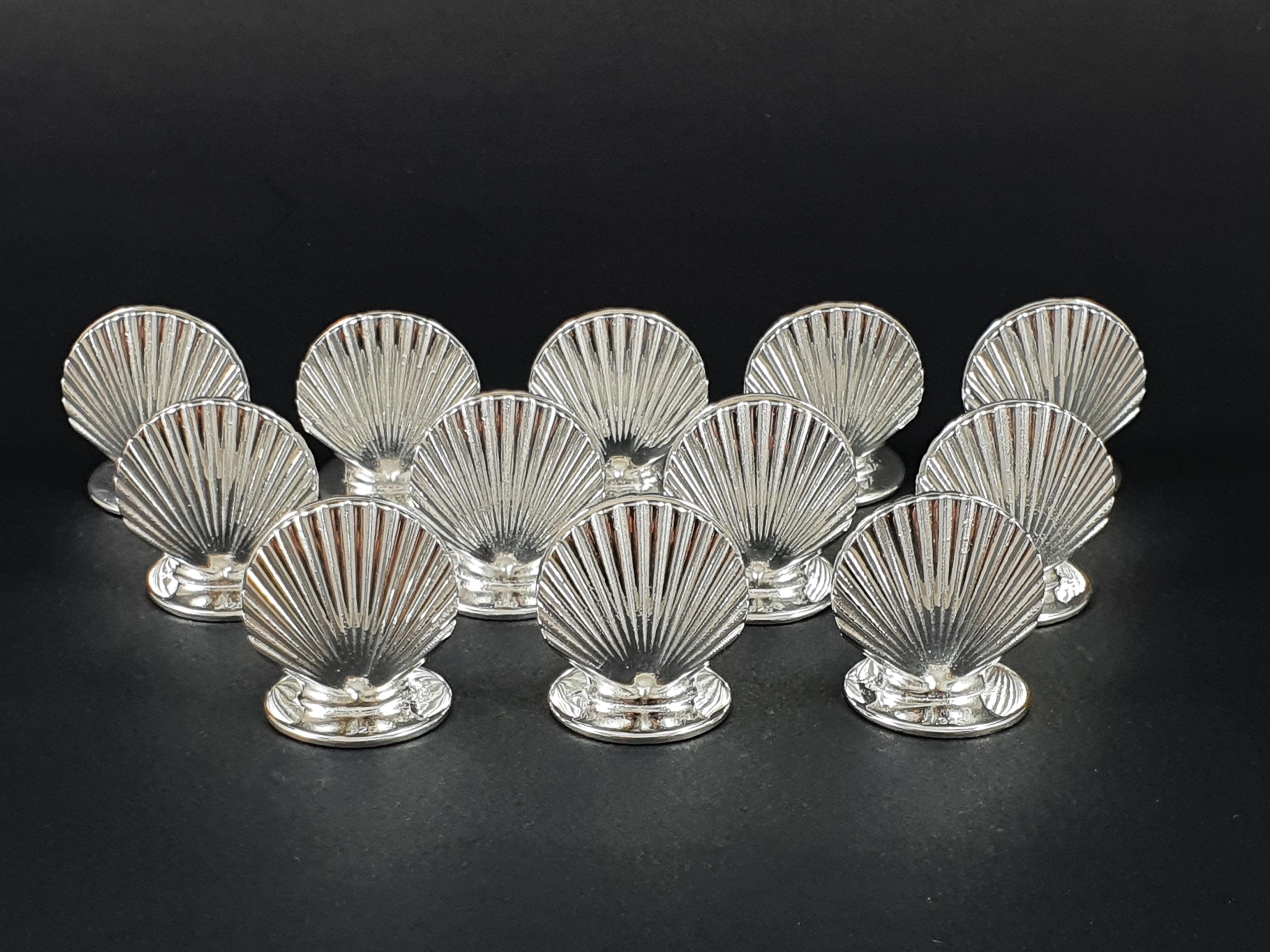 12 Sterling Silver place card holders shell 

Decorated with shells on both sides 

925 silver hallmark 

Height: 2.5 cm 
Base diameter: 2 cm 
Weight: 160 grams

in perfect condition