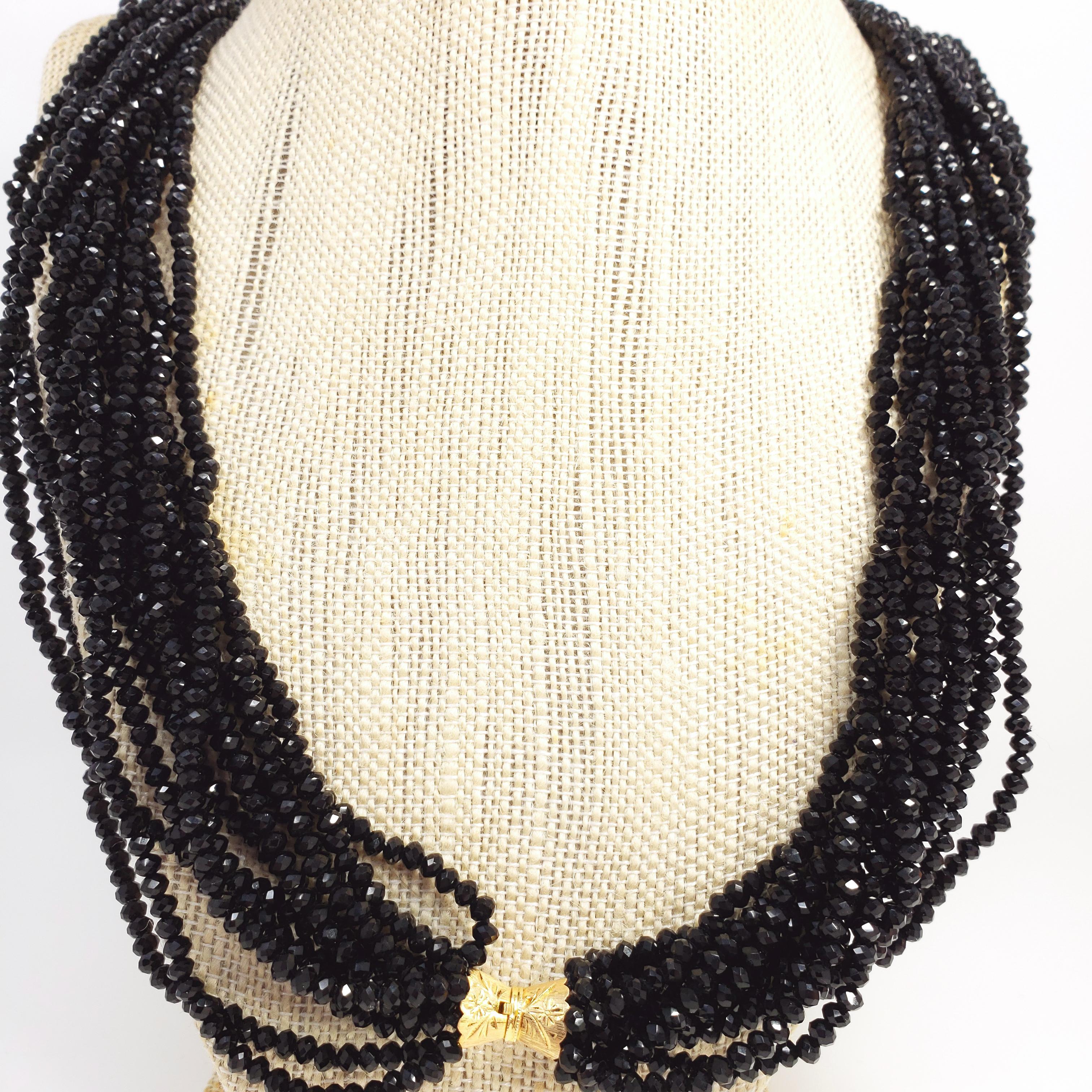 Diese elegante Halskette besteht aus 12 Strängen funkelnder schwarzer Glasspinellperlen, die mit einem Verschluss aus 14-karätigem Gelbgold verbunden sind. Ein luxuriöses Accessoire!

Punzierungen: 14K, 585
Stilisierter goldener Kastenverschluss,