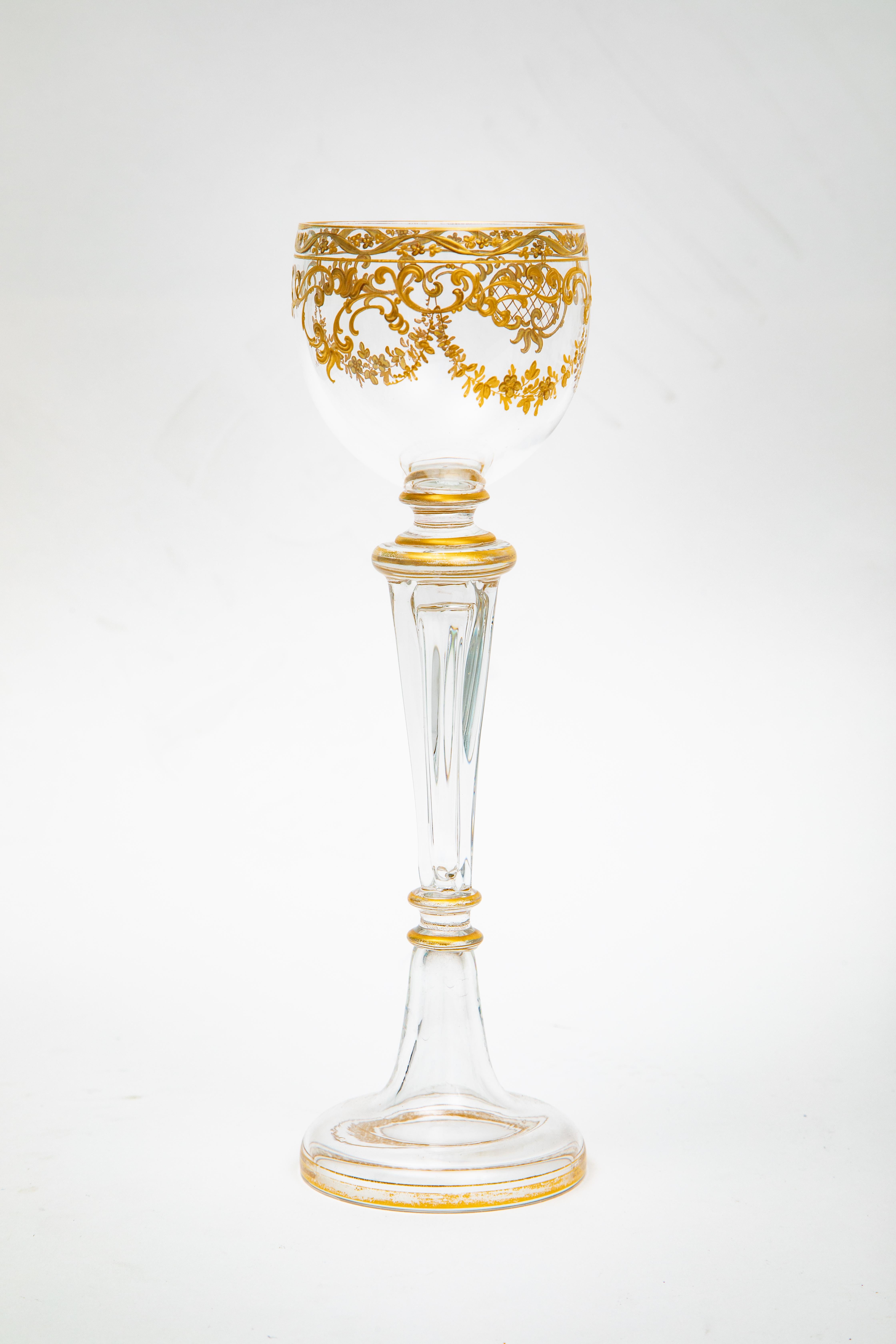 Precioso y elegante juego de 12 copas de vino del último cuarto del siglo XIX. Son altas, miden ocho pulgadas y media y presentan un elaborado tallo soplado con preciosos diseños dorados en forma de guirnalda foliada en las copas. La base está