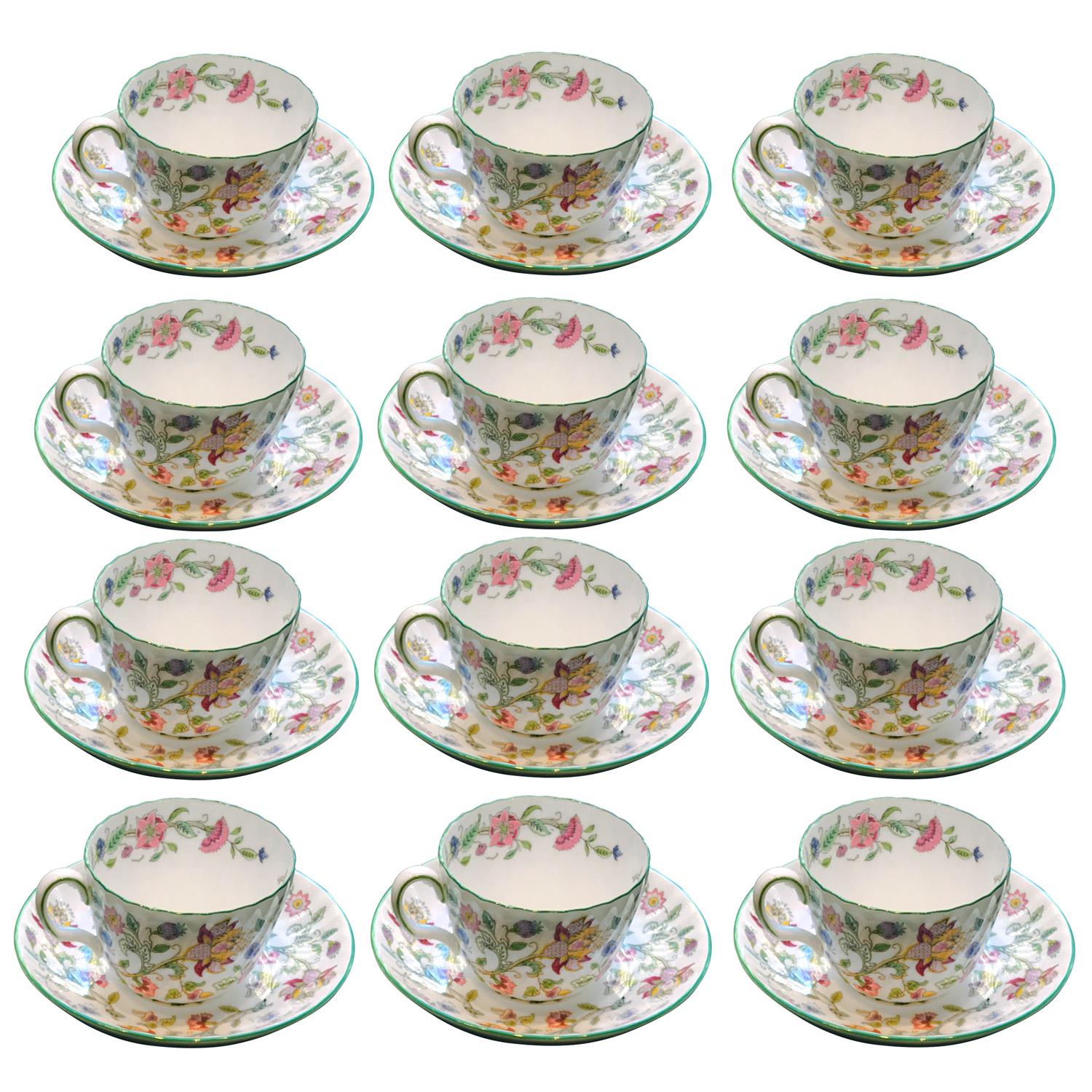 Juego de 12 tazas de té y sus platillos en porcelana Minton Bone China. Famoso modelo Minton Haddon Hall diseñado por John William Wadsworth (1879-1955), reconocible por su cuerpo estriado y fondo blanco decorado con flores de colores como dalias,