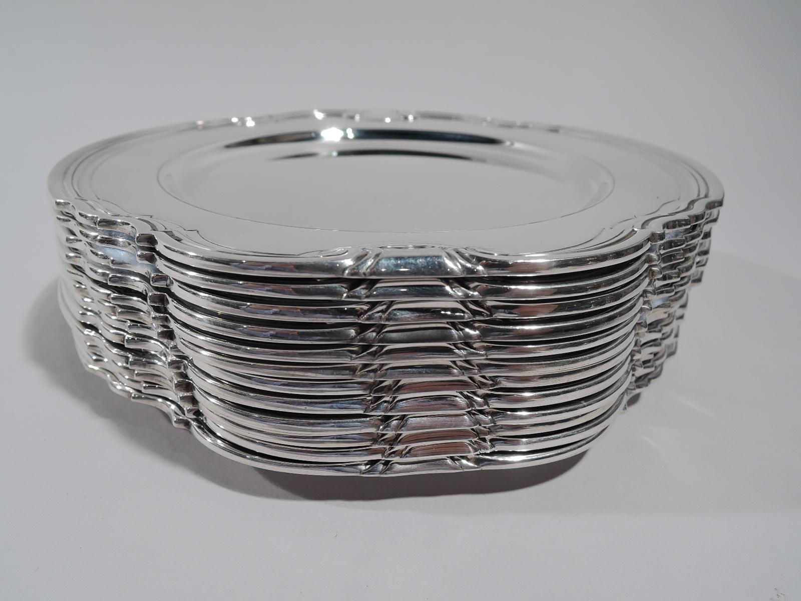 Set of 12 Castilian sterling silver bread and butter plates. Made by Tiffany & Co. in New York, circa 1929. Round with deep well. Shaped and molded rim with stylized volute scrolls. Super stylish in a less well-known Art Deco pattern. Fully marked