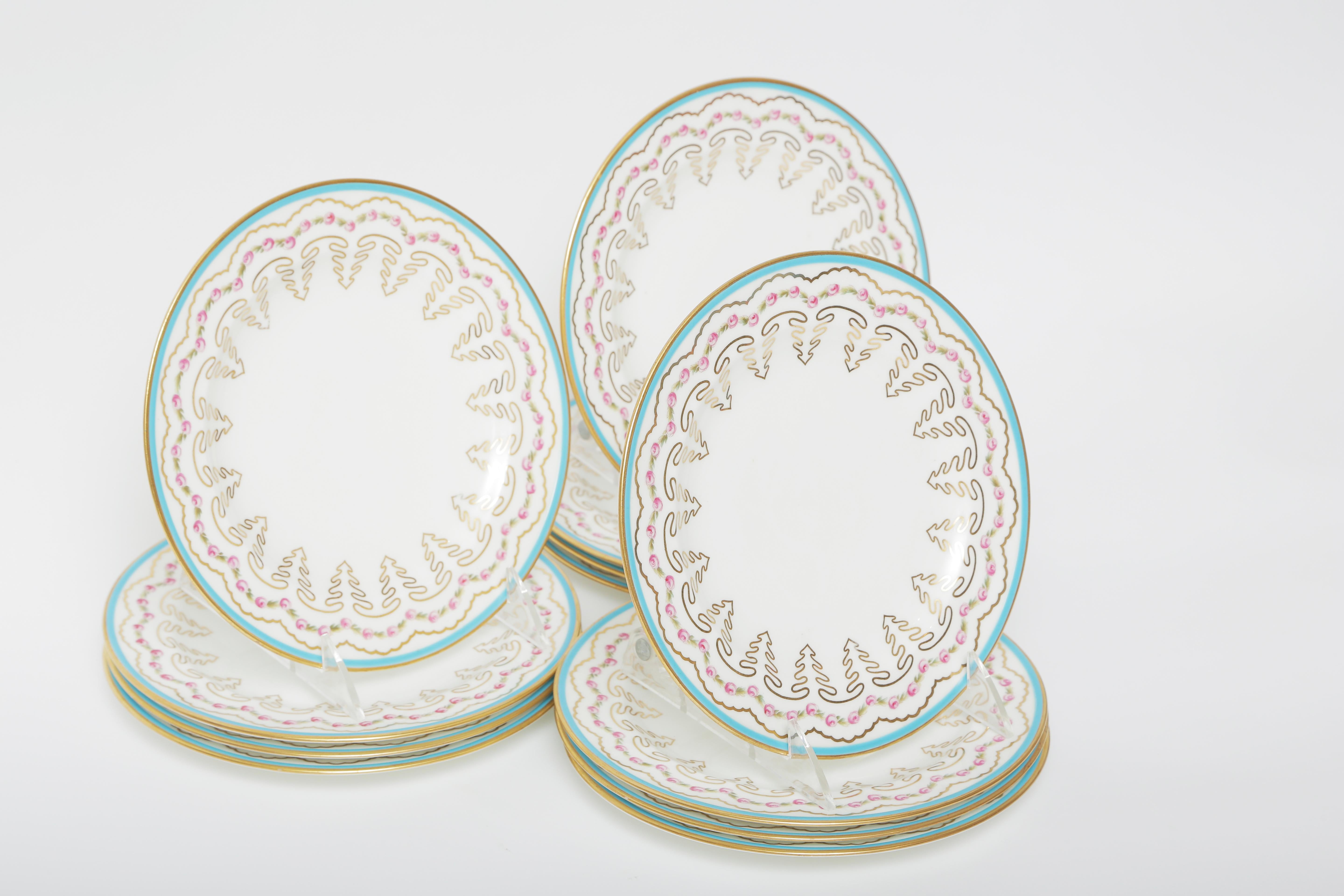 A pretty set of first course, salad or dessert plates by the Gilded Age Porcelain firm of Cauldon, England. This set features a turquoise border, hand painted roses and an interesting gilt design through the collar of the plate. A crisp white