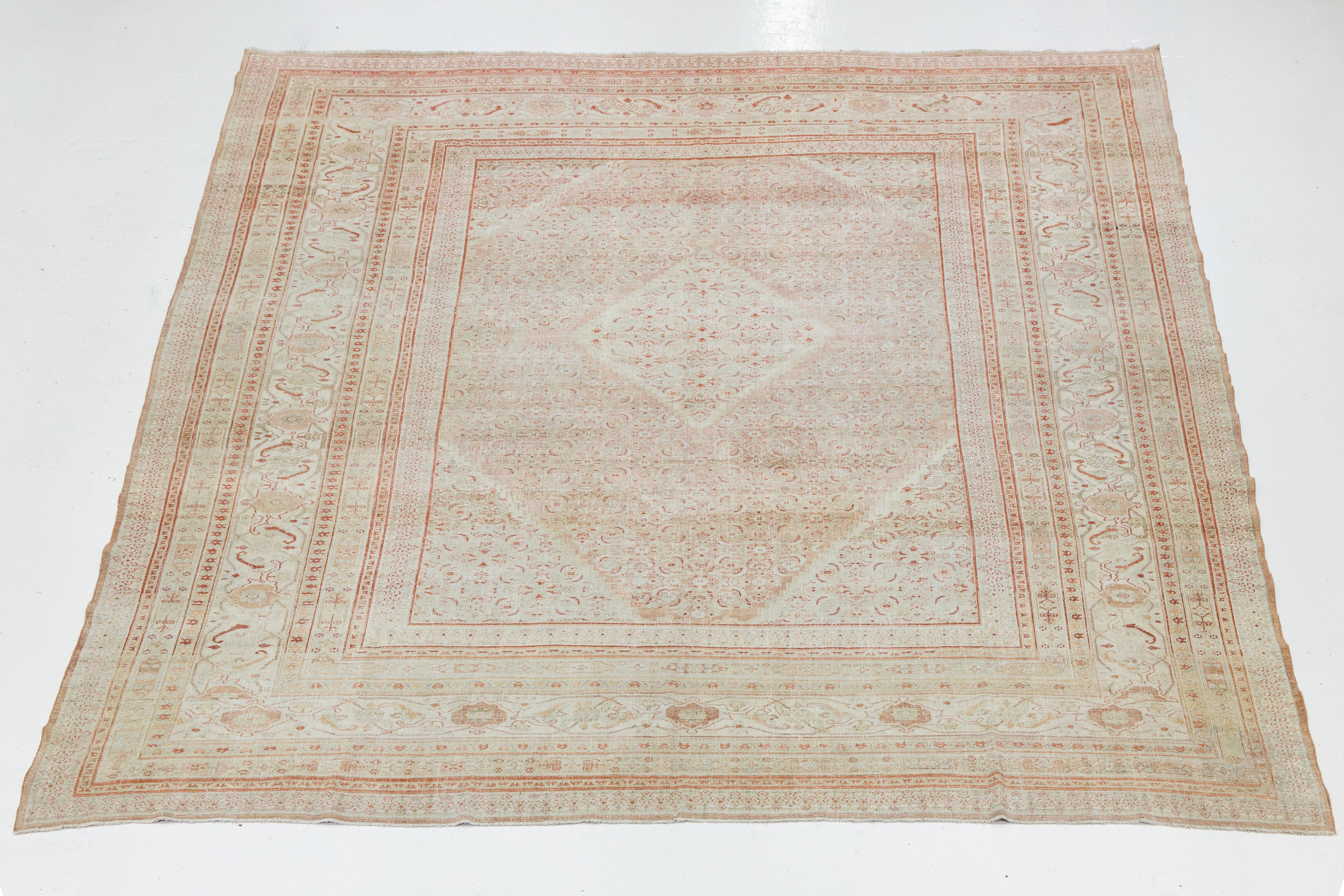 Dieser atemberaubende antike Täbriz-Teppich ist aus Wolle handgeknüpft und zeigt ein wunderschönes Pfirsichfeld. Es ist elegant umrahmt mit Akzenten in Rost, Beige und Blau, die einen schönen Kontrast zu dem filigranen, floralen Allover-Design