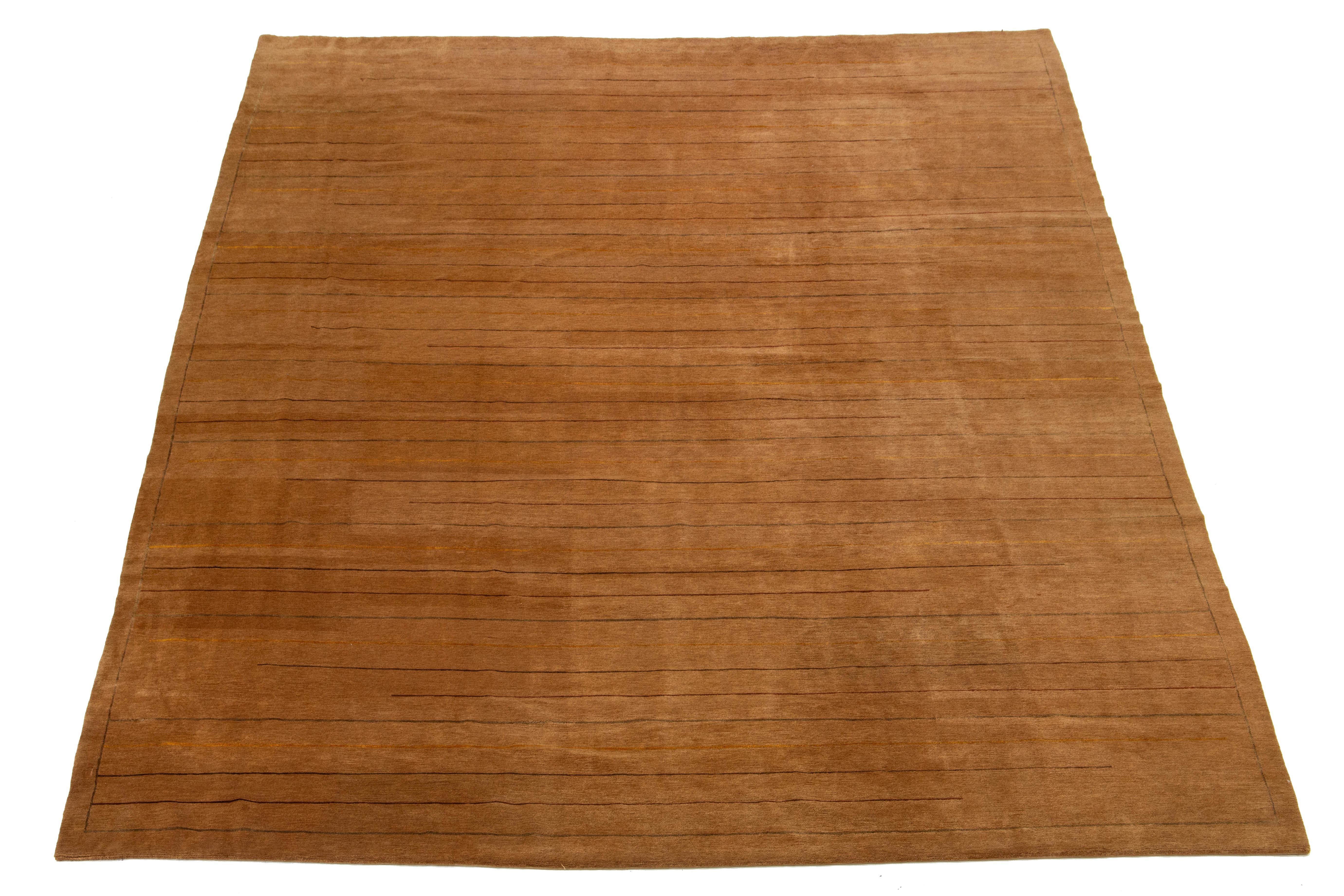 Ce tapis contemporain en tissage tibétain présente un motif rayé multicolore qui attire le regard. Fabriqué en laine ou en soie tibétaine de première qualité, il présente des détails complexes et met en valeur un riche champ de couleurs brun