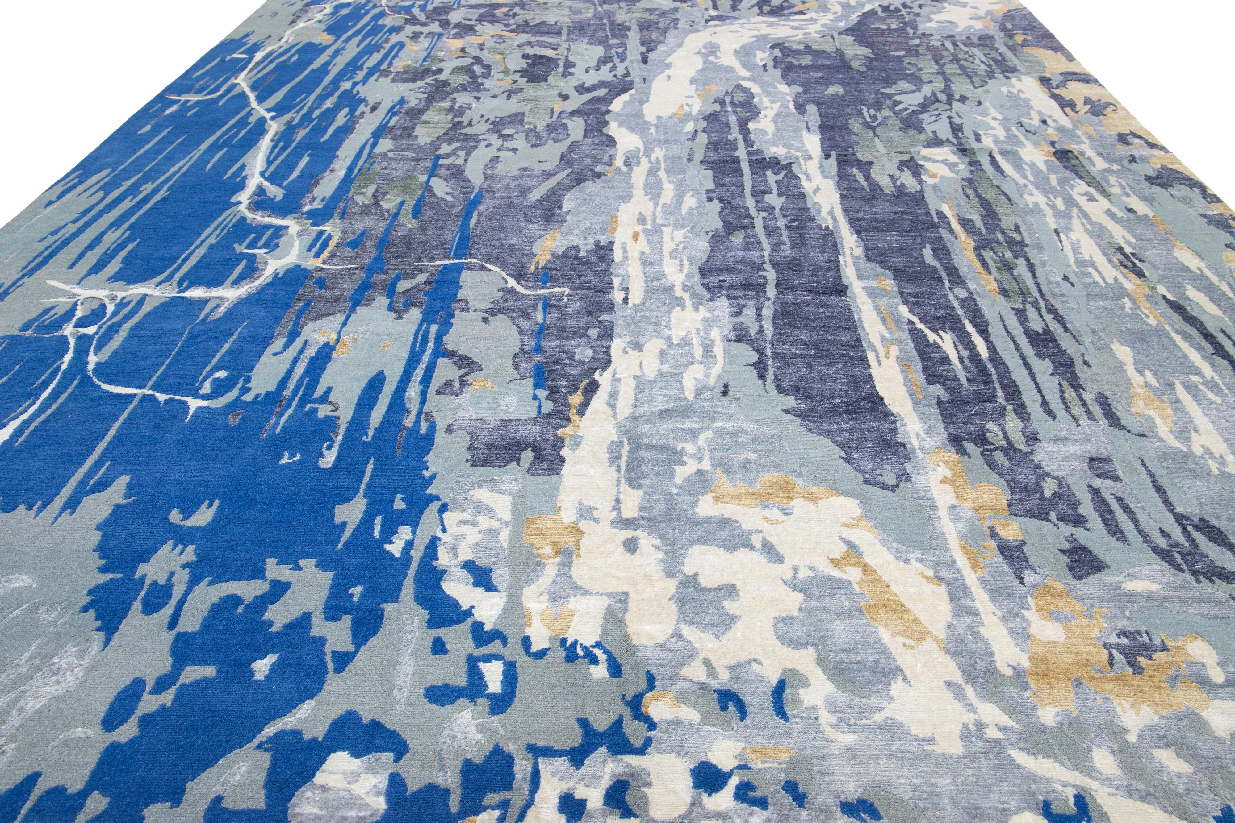 Questo tappeto contemporaneo annodato a mano presenta uno splendido disegno astratto dai colori vivaci che cattura l'attenzione senza sforzo. Realizzato in lana o seta di alta qualità, presenta uno sfondo grigio, blu e oro che mette in risalto i