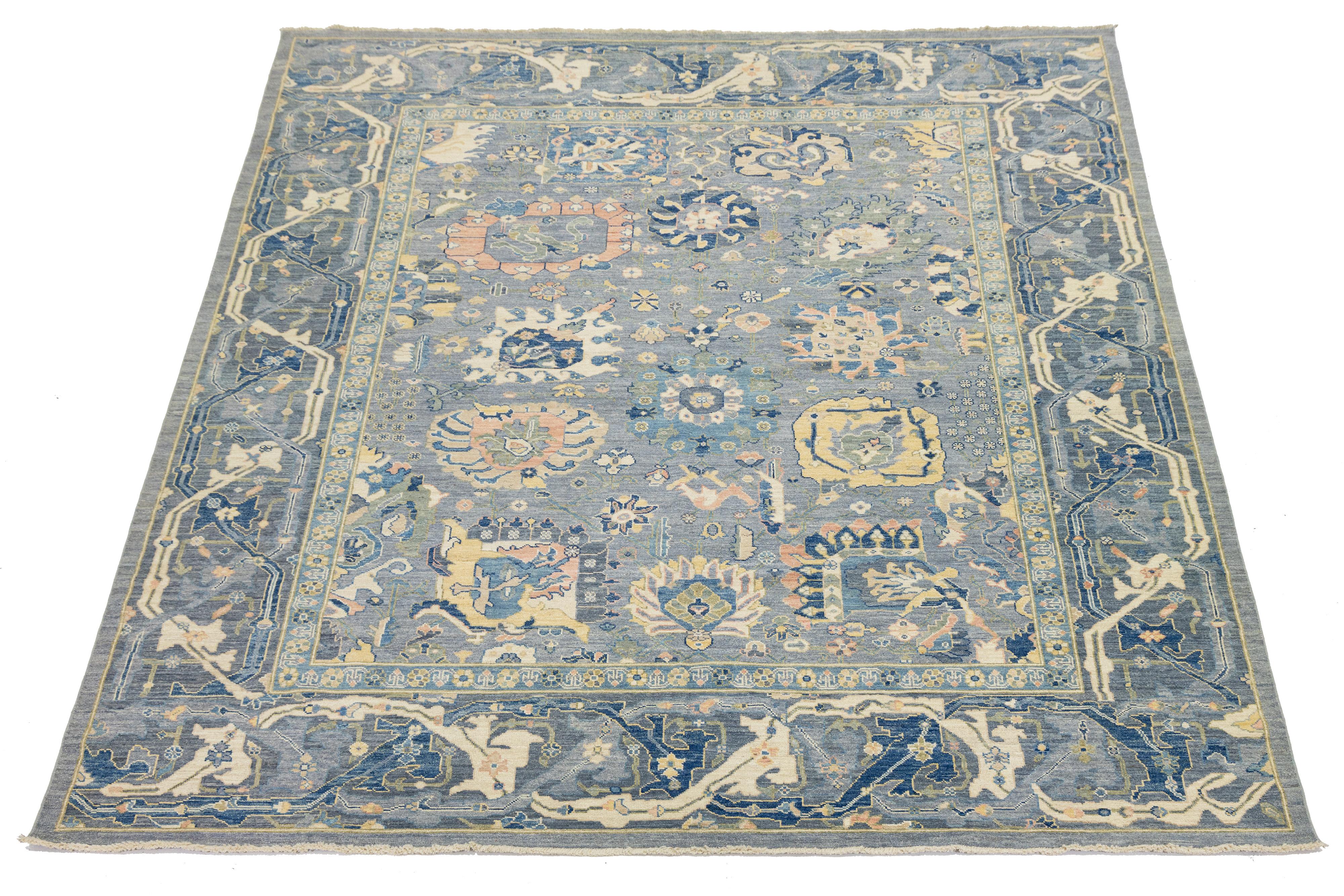 Questo moderno tappeto in lana in stile Oushak, annodato a mano, presenta un sottile sfondo blu ornato da motivi floreali. Il suo design combina l'estetica contemporanea con l'artigianato tradizionale di Oushak. I colori e i motivi vivaci possono