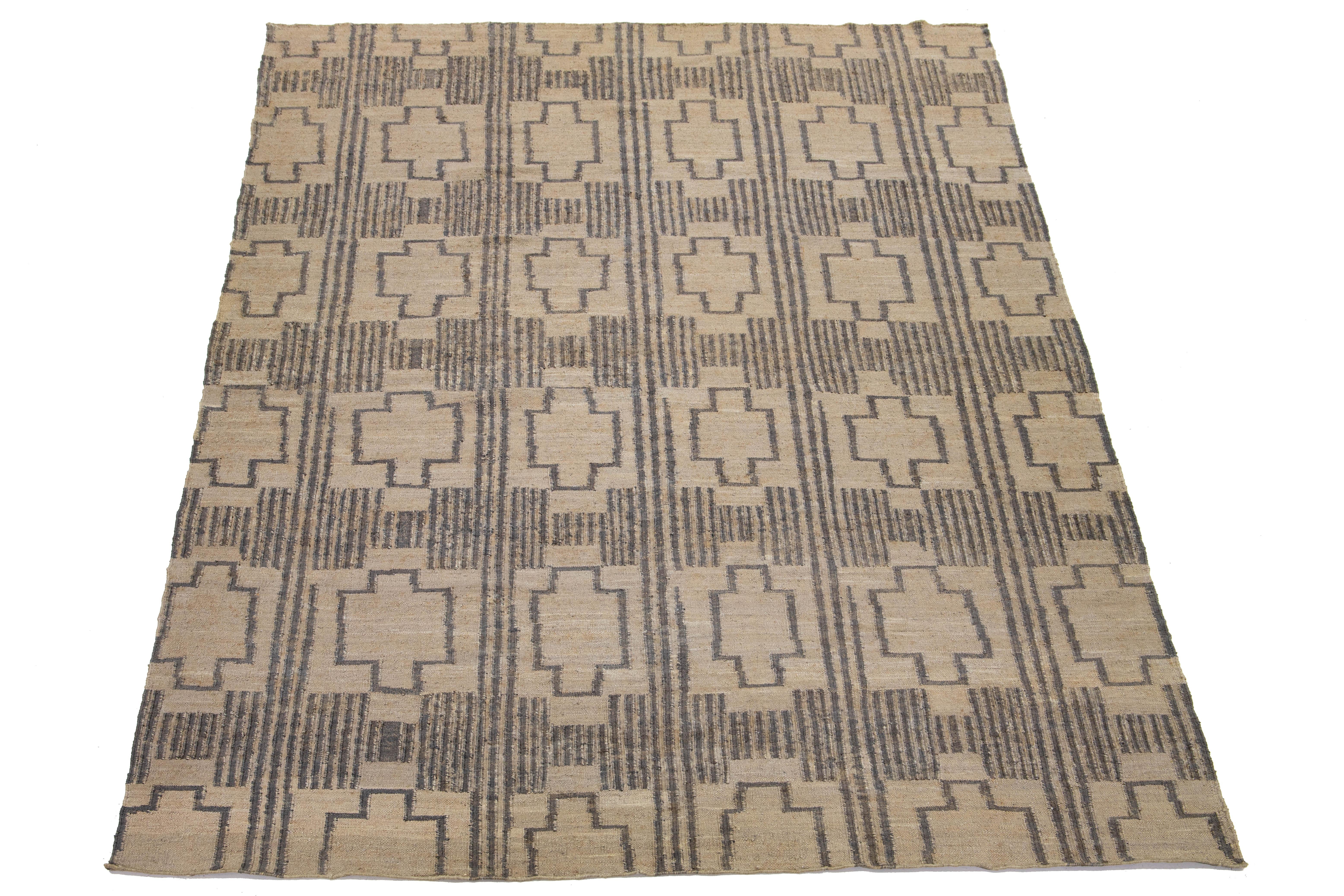 This flatweave natural jute rug showcases a contemporary Dhurrie design, featuring a tan-beige base color and stylish gray geometric accents.

 This rug measures 10'6