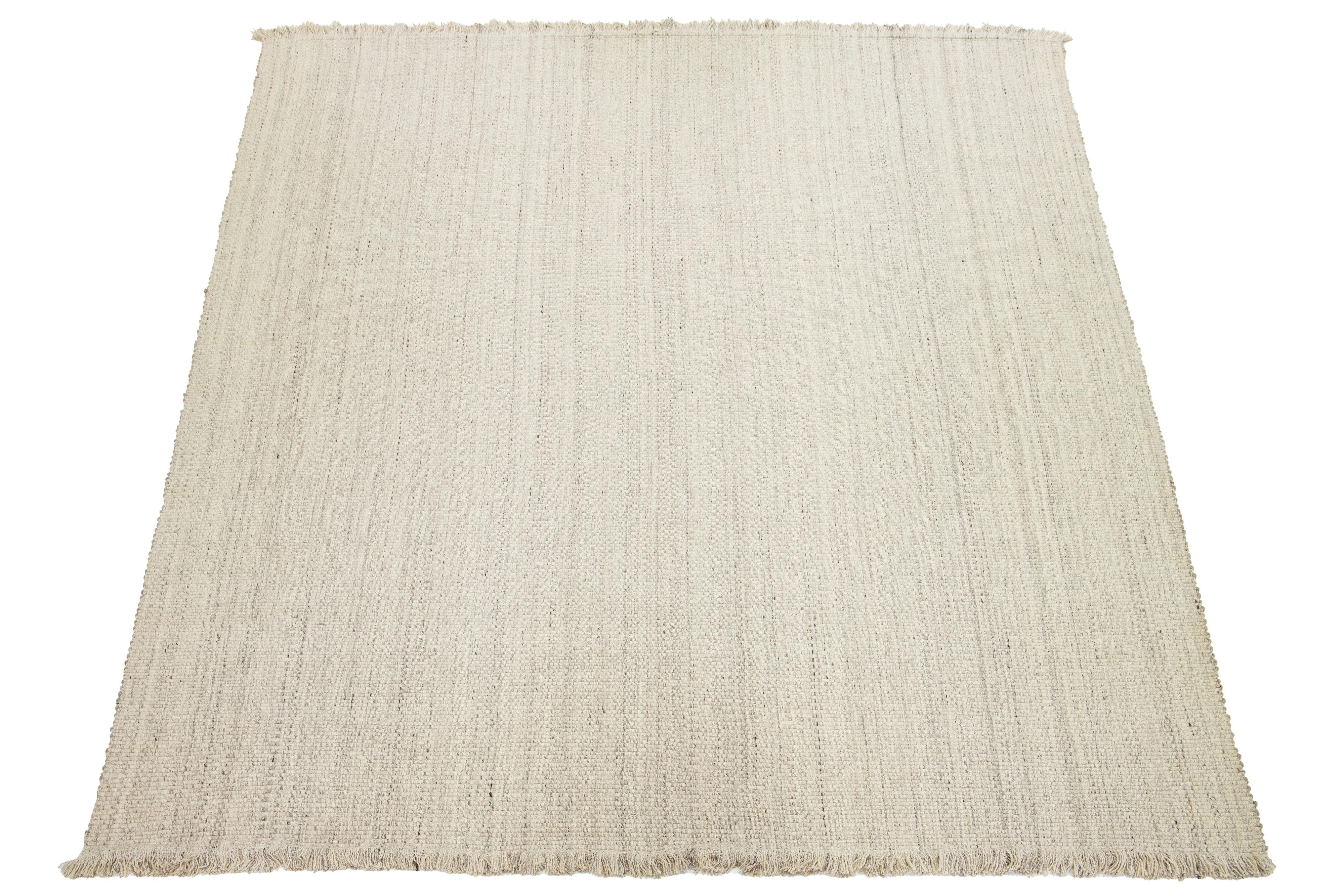 Questo tappeto presenta un moderno design organico a trama piatta in lana Kilim di Apadana con un motivo di base avorio.

Questo tappeto misura 12'3