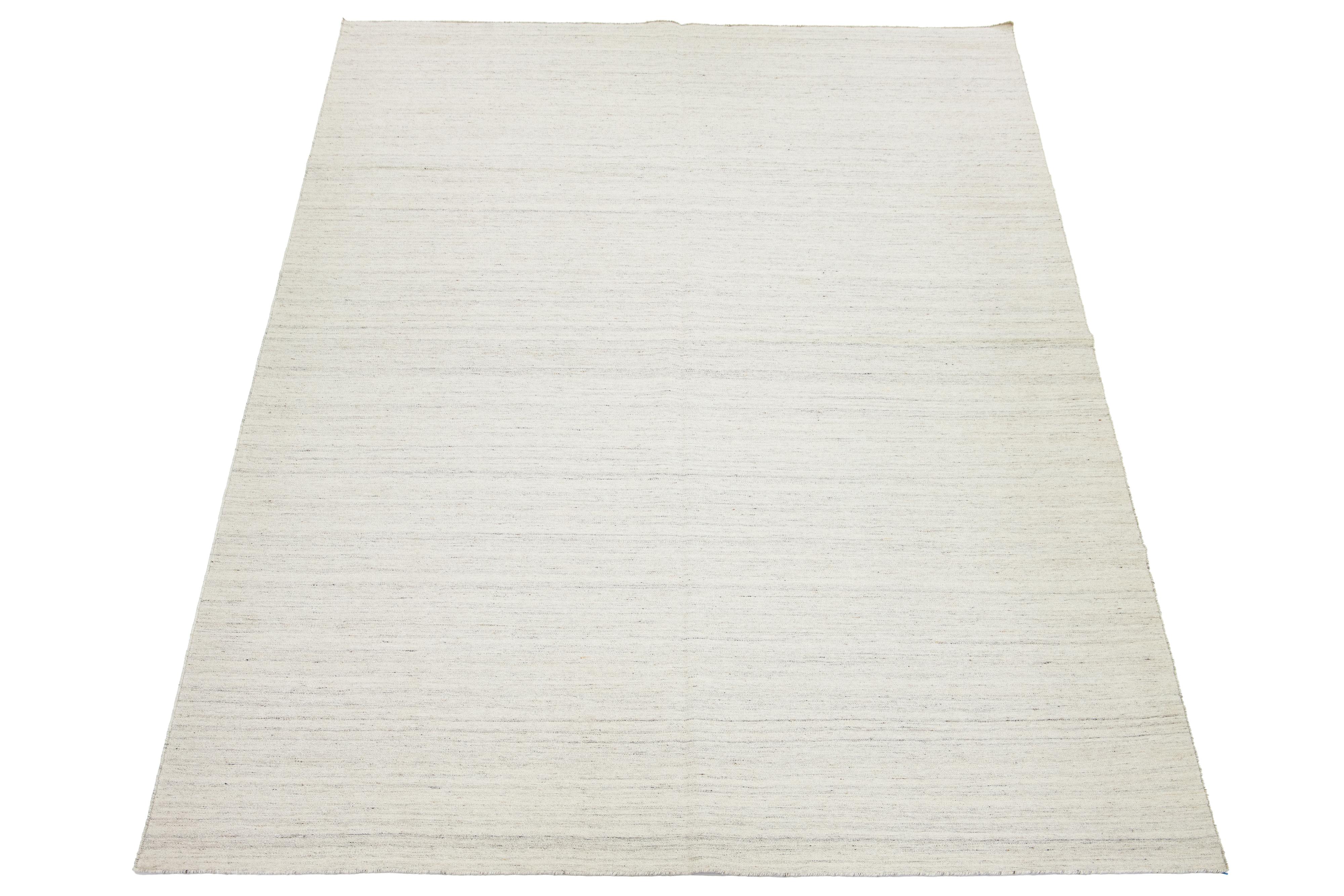 Dieser Teppich zeichnet sich durch ein modernes Kilim-Flachgewebedesign aus Wolle aus, das ein gestreiftes graues und elfenbeinfarbenes Grundmuster aufweist. 

Dieser Teppich misst 10' x 15'.


