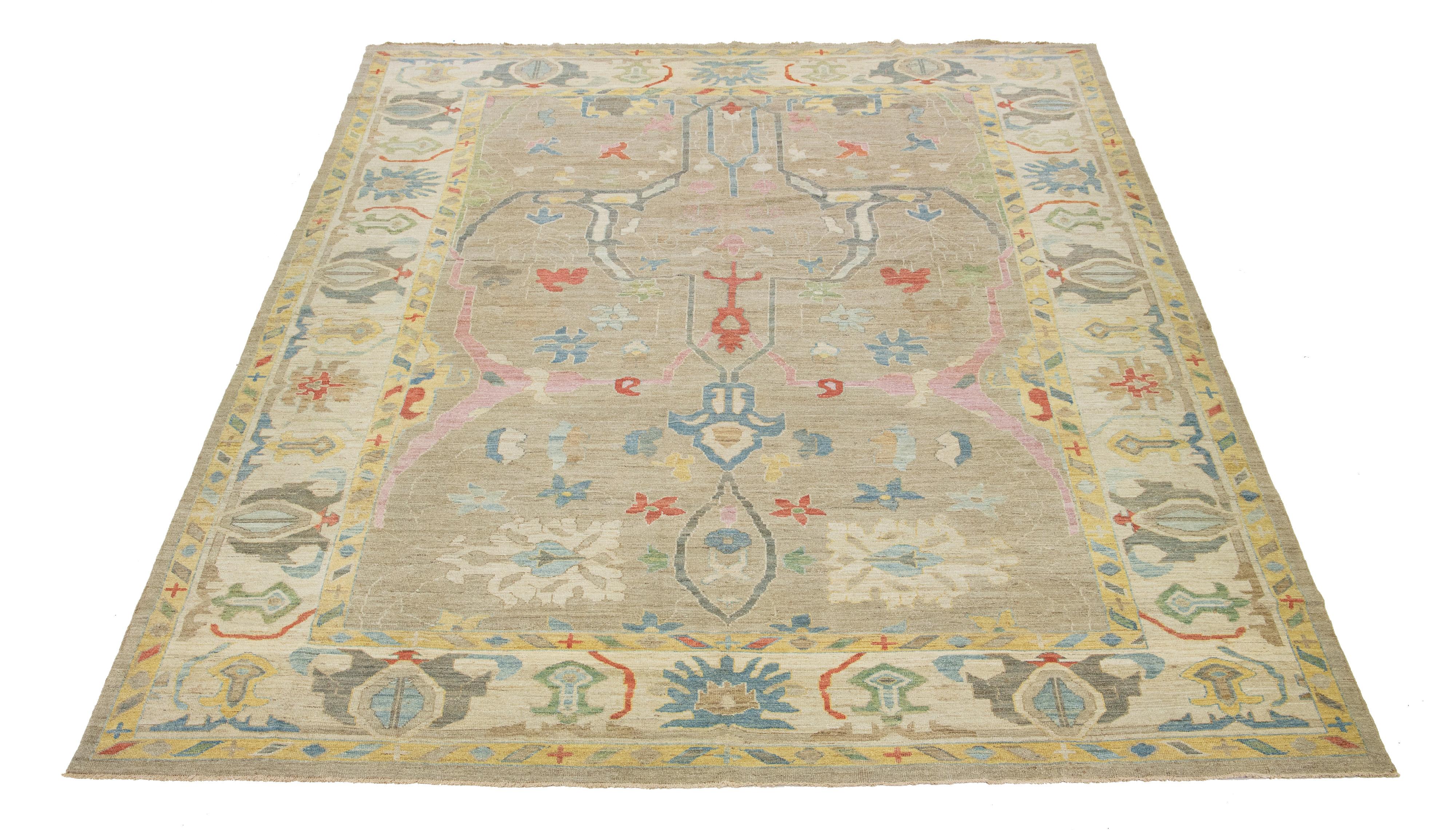 Questo tappeto in lana annodato a mano ha uno sfondo marrone chiaro ornato da un disegno floreale blu, rosa e arancione.

Questo tappeto misura 11'11'' x 15'6''.