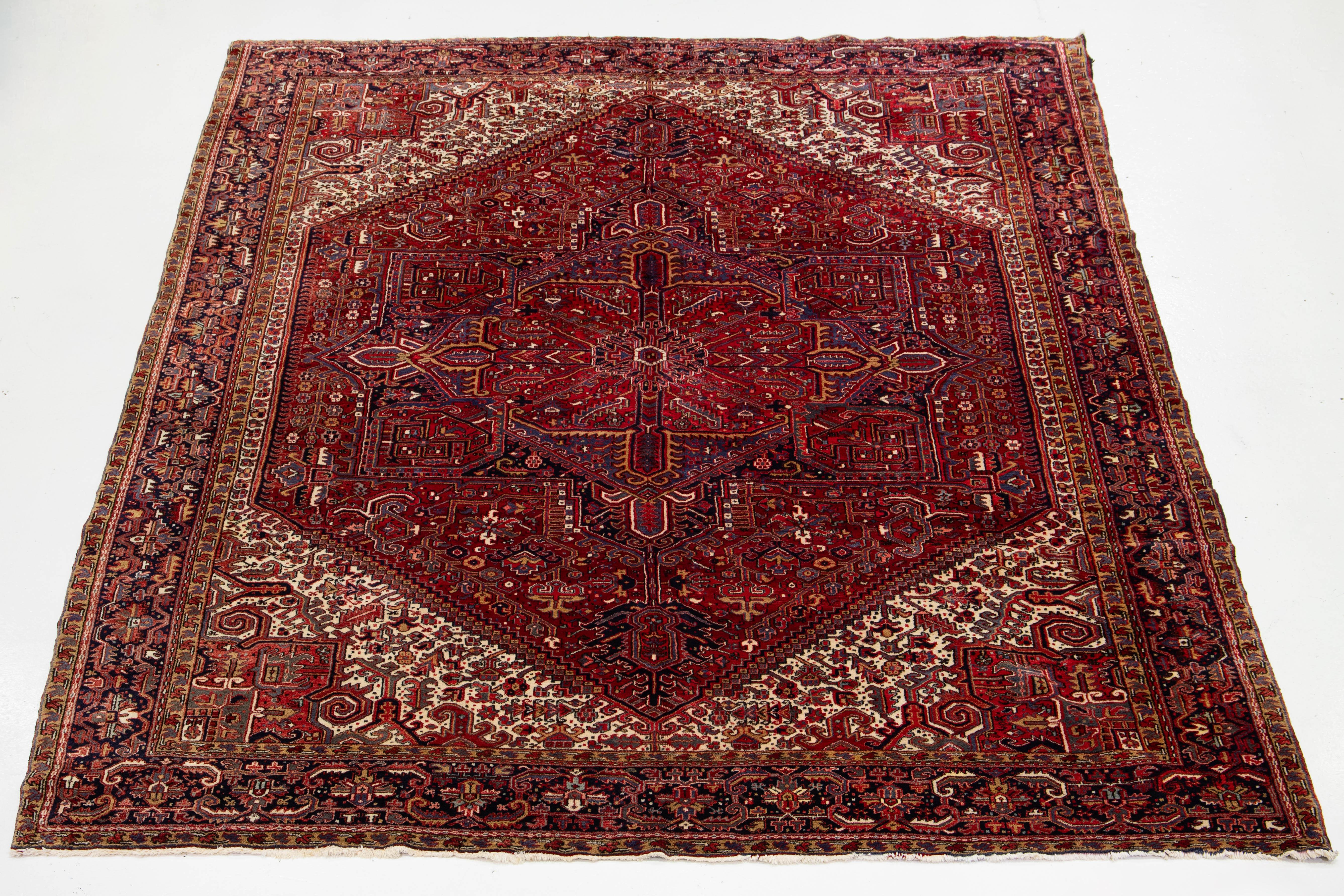 Experience the timeless elegance of this stunning vintage Persian Heriz rug, showcasing a vibrant red field. At its heart lies a captivating medallion design, beautifully enhanced by a harmonious array of multicolored accents, making it a striking