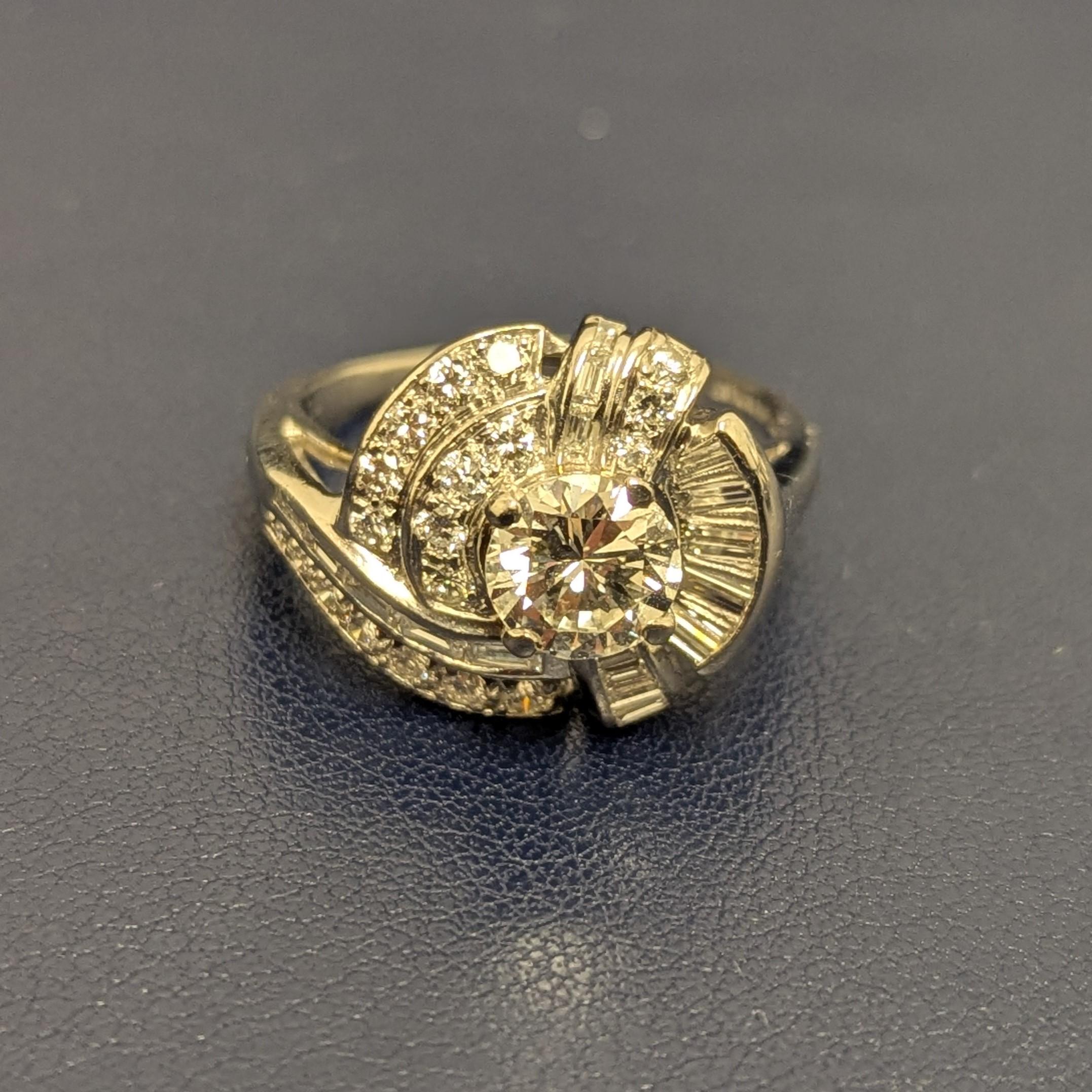 Cette bague, qui peut être considérée comme une bague de fiançailles ou de cocktail, contient un diamant rond central de taille brillant, pesant environ 1,20 carats, qui est magnifiquement entouré de 17 diamants baguettes et de 19 diamants ronds de