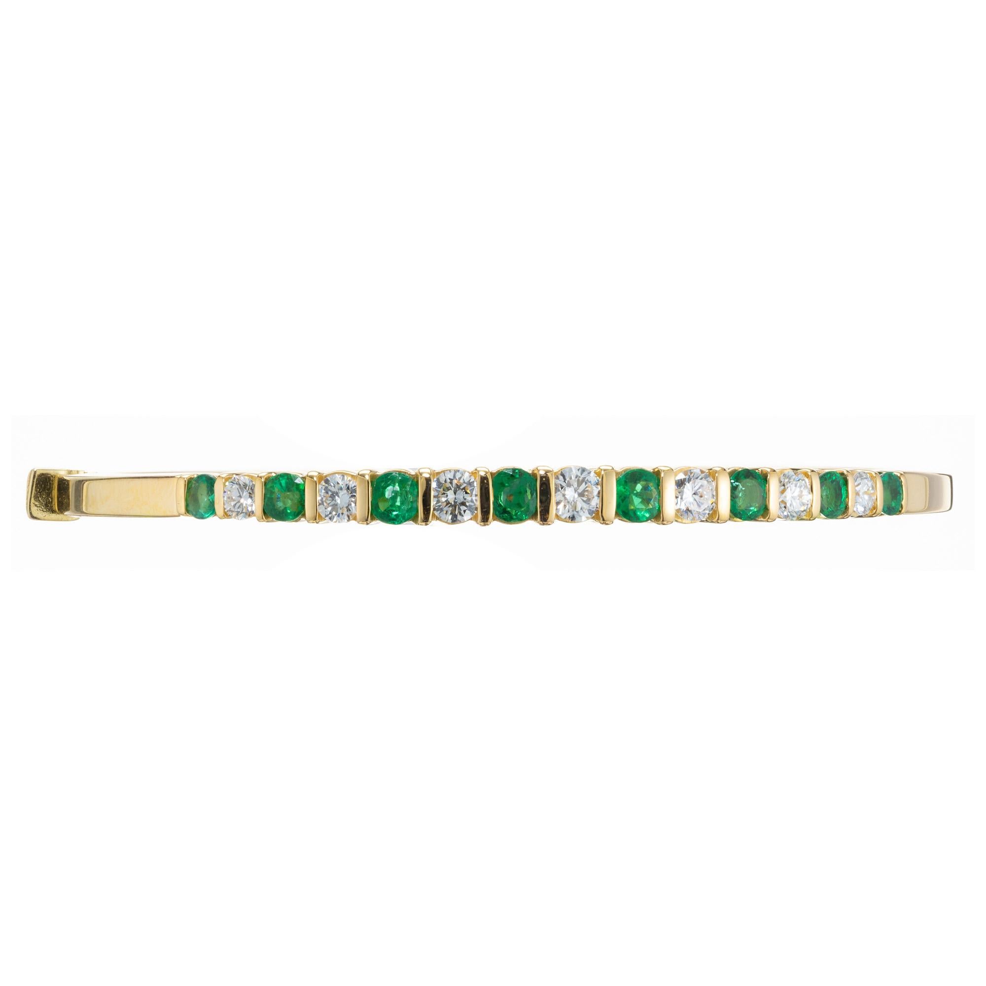 Emerald and diamond 18k yellow gold bangle bracelet. 8 round cut emeralds totaling 1.20cts that alternate with 7 round brilliant cut diamonds. The stone are separated by yellow gold bars. The emeralds are crisp and bright green complemented by