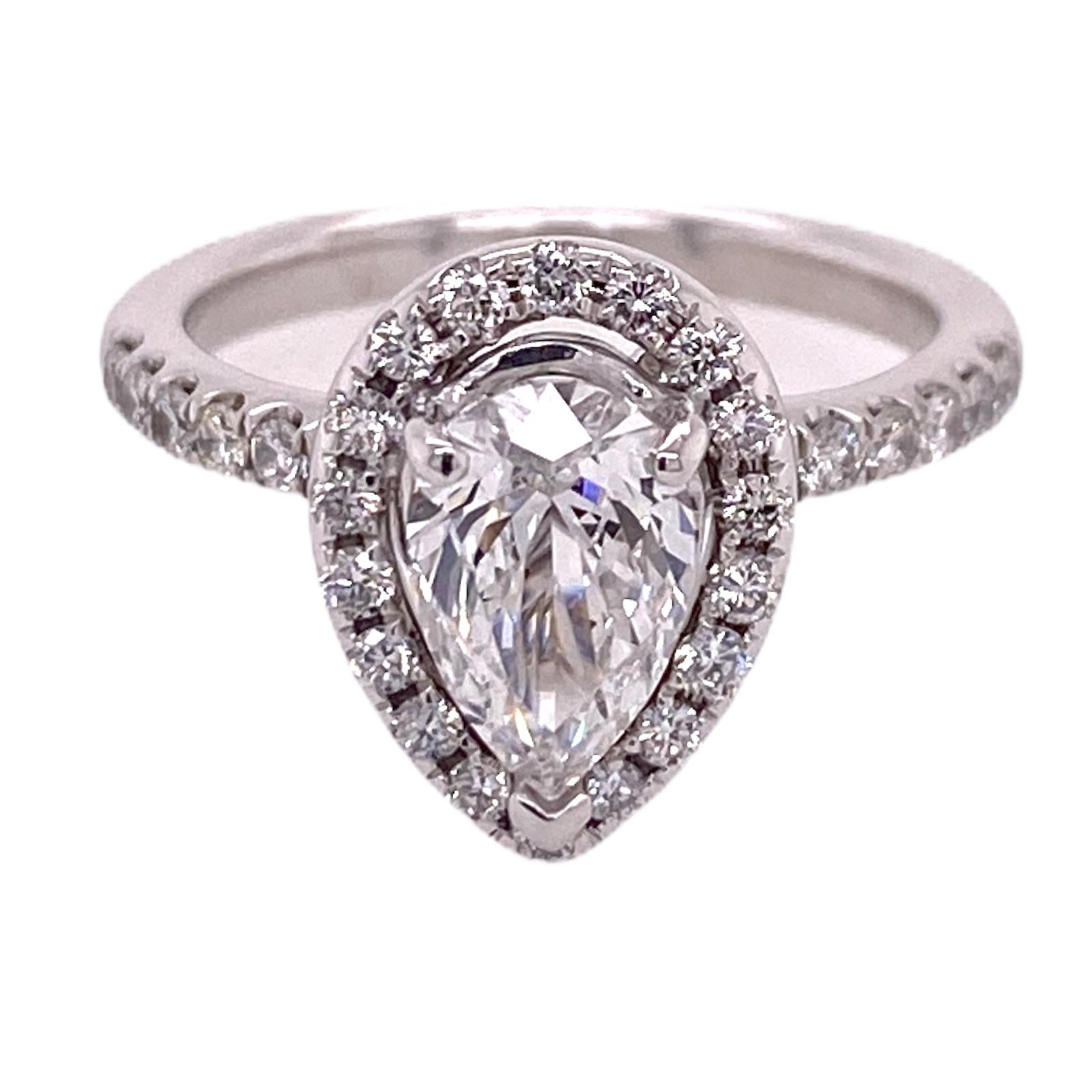 Beautiful pear cut diamond halo engagement ring fashioned in 14 karat white gold. The pear cut diamond weighs 1.20 carats and is graded F color and SI2 clarity by the GIA. The pear is surrounded by a diamond halo featuring 32 round brilliant cut