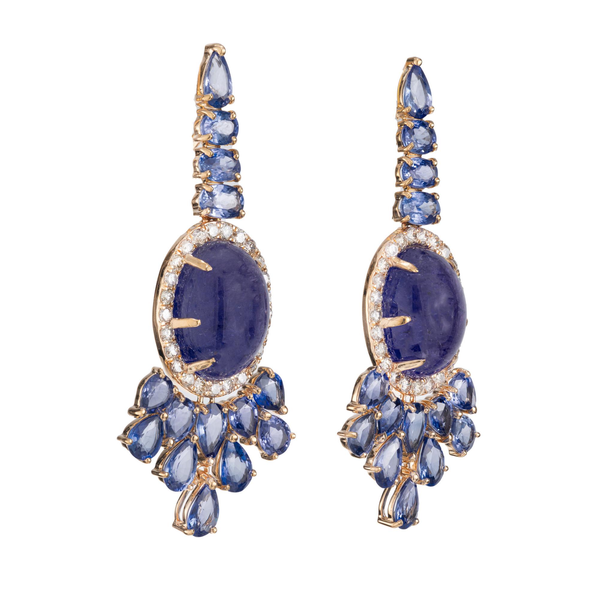 Spectacular Tanzanite, Sapphire and diamond dangle earrings. 2 vibrant oval cabochon tanzanite gemstones totaling 12.00cts are known for their exquisite blue-violet hue, are the centerpiece of these earrings. They are mounted in 18k yellow gold clip