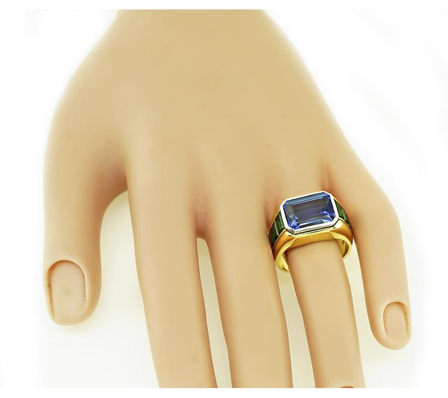 Questo è uno splendido anello in oro giallo e bianco a 18 carati. L'anello è centrato da un'incantevole tanzanite taglio smeraldo che pesa circa 12,00ct. La tanzanite è accentuata da deliziosi accenti di tormalina verde. La parte superiore