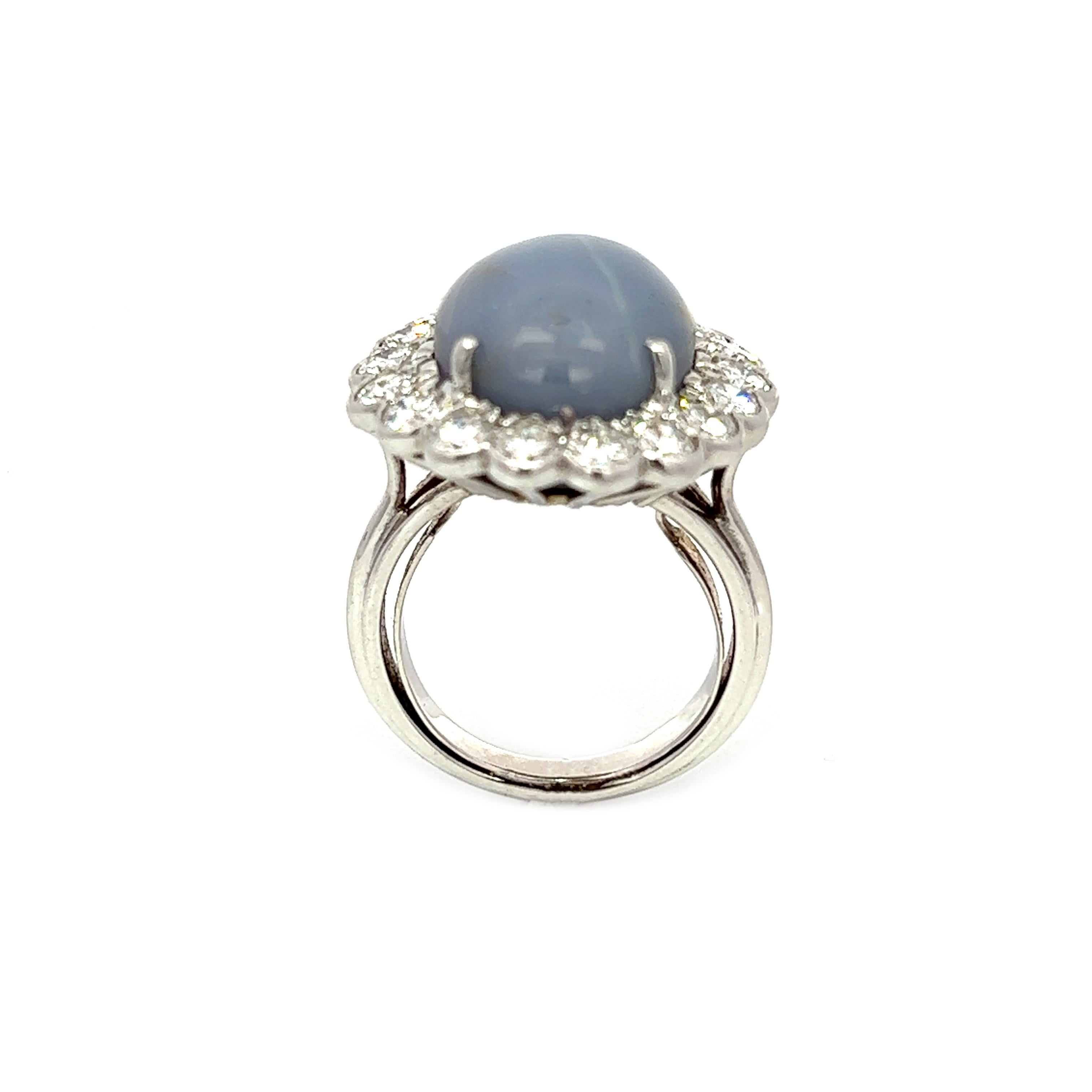 Cette bague exquise est ornée d'un saphir étoilé de 9,32 carats qui, sous certaines conditions d'éclairage, reflète un étonnant motif étoilé, comme le montrent certaines des images. Le saphir est entouré de 18 diamants de couleur H et de pureté VS,