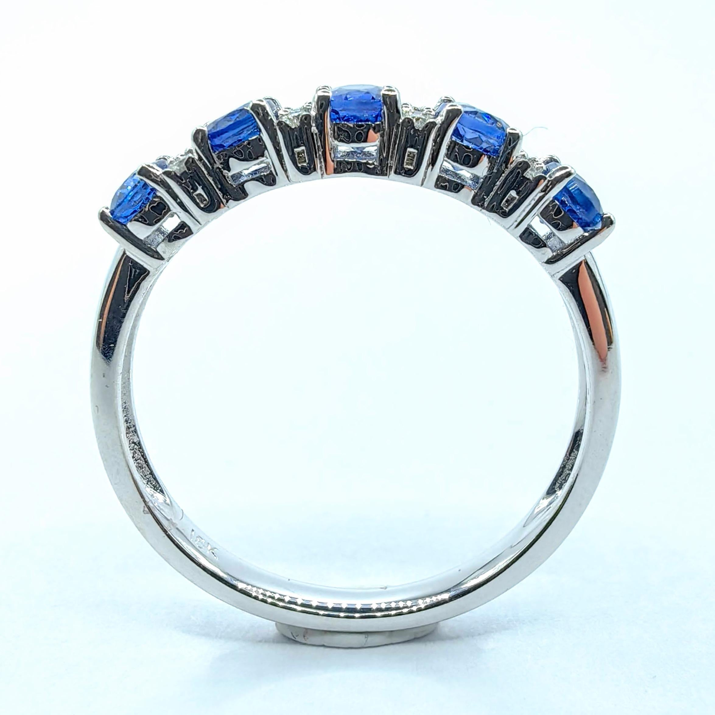 A refined expression of timeless elegance, this 18K white gold eternity band ring showcases a symphony of five oval-cut blue sapphires, totaling approximately 1.20 carats. Each sapphire is individually prong-set to maximize brilliance and clarity,