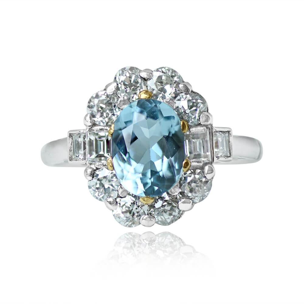 This gemstone ring features a 1.20-carat oval-cut aquamarine set in yellow gold prongs. It's adorned with a floral halo of old European cut diamonds around the center stone, while baguette-cut diamonds accent the shoulders. The total diamond weight