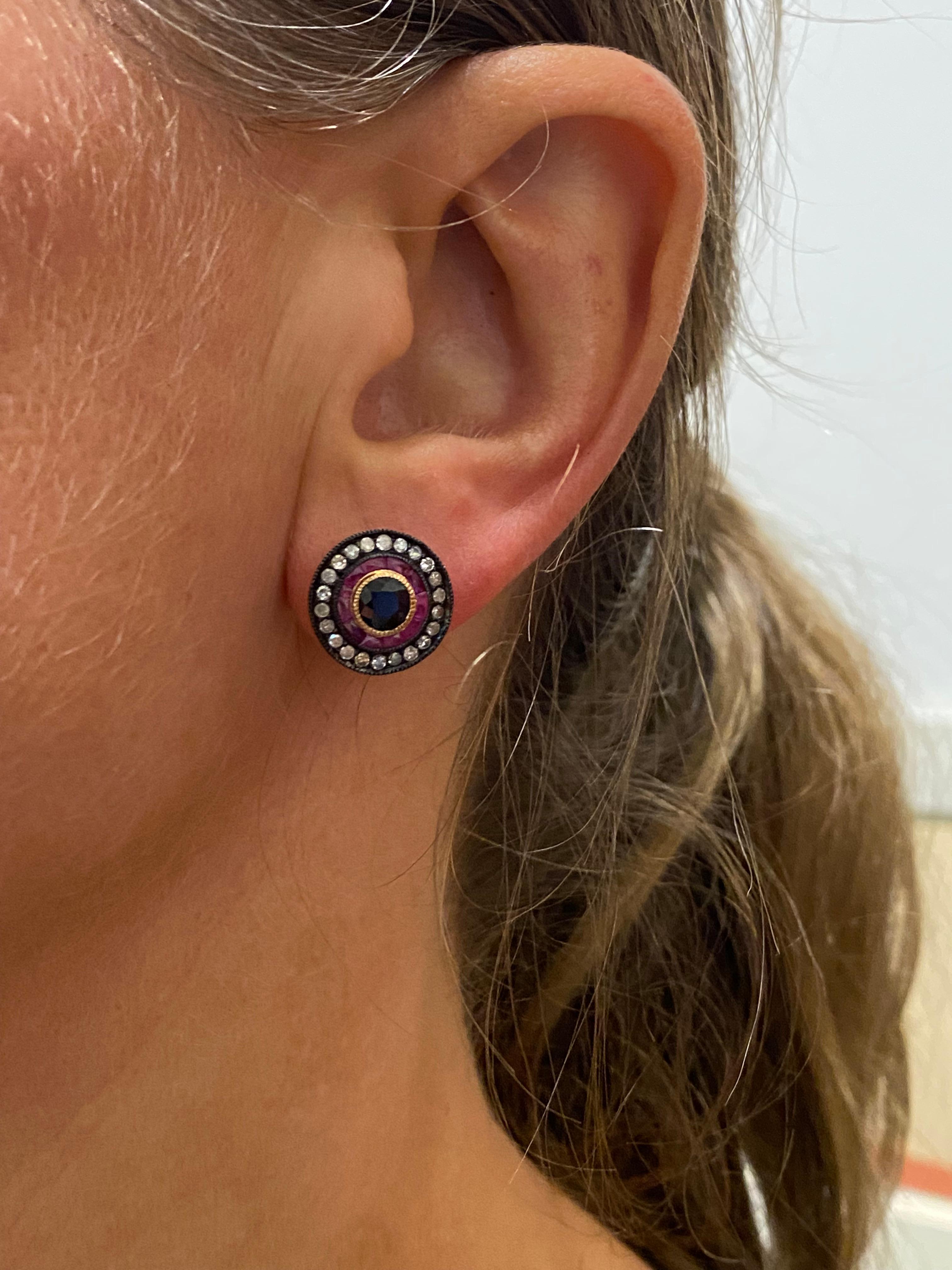 Striking & stylish these vintage studs were 
meticulously crafted in 9K Rose Gold

Each is feating a 0.60ct 
Natural Midnight Blue Sappphire,
bezel set & 
surrounded by the row of caliber cut 
natural rubies of pinkish red colour, 

Further