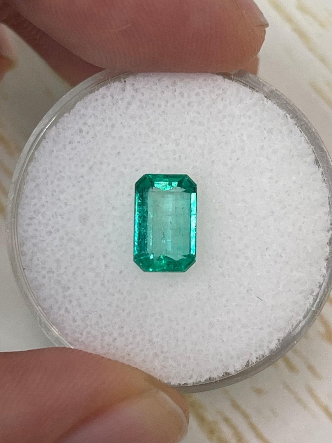 Stone: Emerald
Weight: 1.21-carats
Shape: Emerald Cut
Clarity: Transparent
Luster: Very Good
Color: Bluish Green
Measurements: 8.43mm x 5.29mm x 3.40mm
Geographic Origin: Colombia
Treatment: Natural, Oiling

Comments: Due to their growth conditions