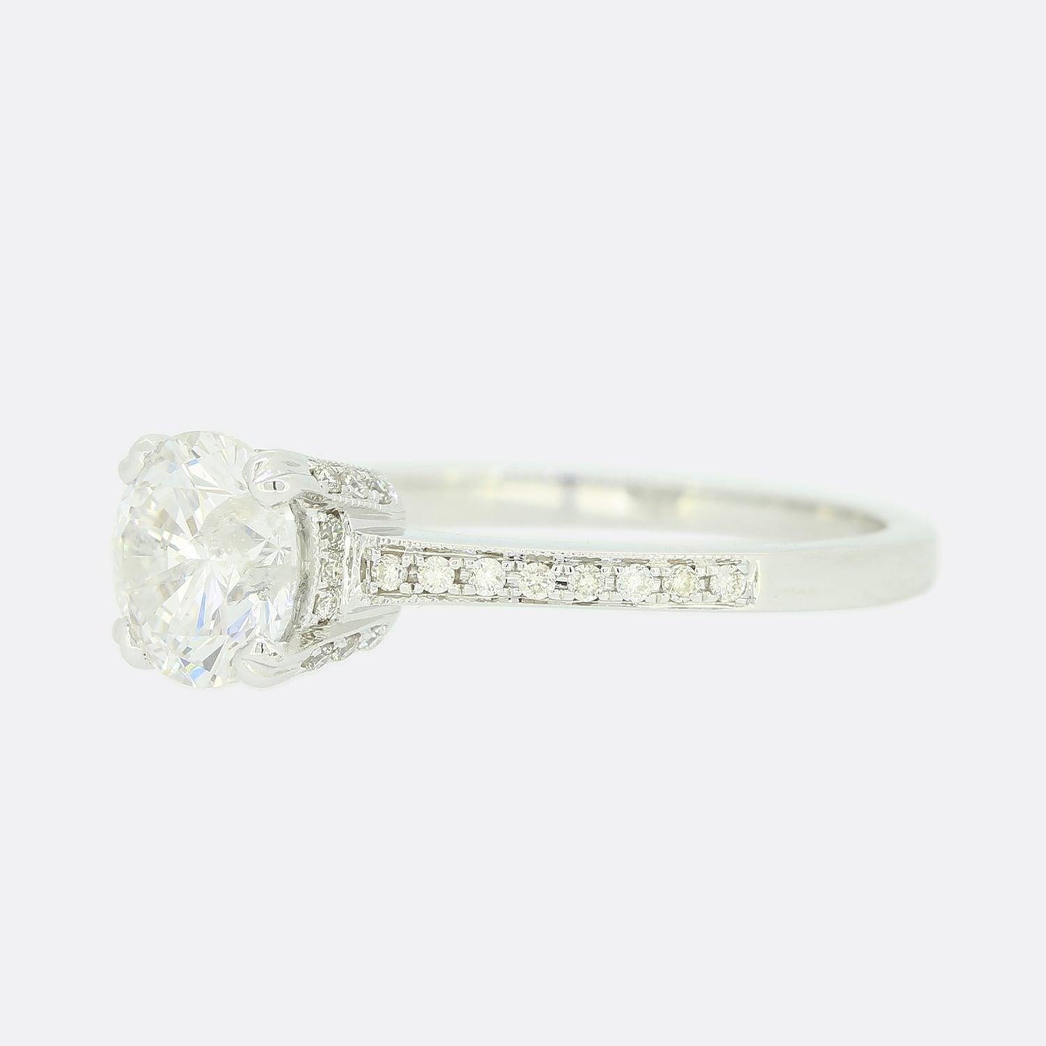 This is an 18ct white gold diamond engagement ring. The round brilliant cut diamond is set in a raised 4 claw mount and each shoulder features 8 smaller diamonds.

Condition: Used (Very Good)
Weight: 3.0 grams
Size: N
Central Diamond Details: 1.21