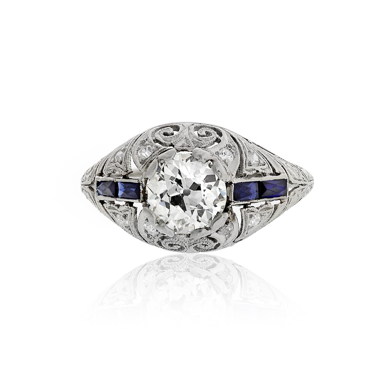 1.21 Carat Old European Cut diamond set in platinum in an Art Deco mounting with accent French-cut sapphires on the sides. 
The Center diamond weighs 1.21 carats and is of J-K color SI1 clarity. 
Size 7
Widest point 7mm.
Openwork filigree gives this