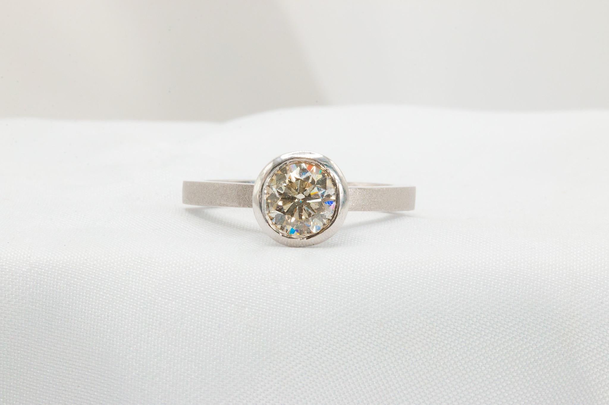 Cette bague de fiançailles unique en son genre apporte une touche étonnante mais de bon goût à la monture solitaire classique, avec son diamant rond de 1,21 carat de taille brillant (couleur estimée I et pureté estimée SI2) dans un chaton poli
