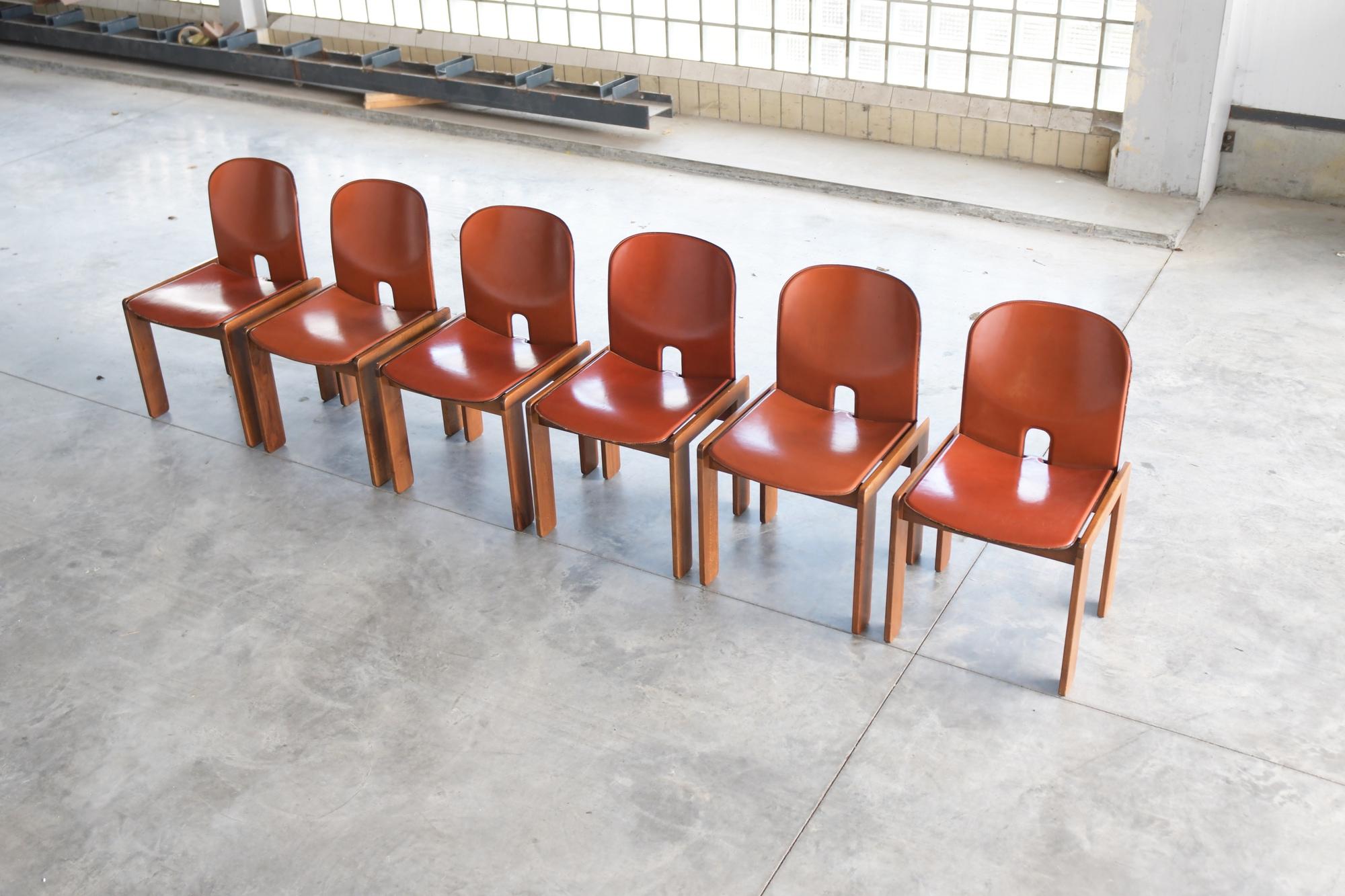 Nice set of 6 ‘121 dining chairs’ designed by Afra & Tobia Scarpa and manufactured by Cassina, Italy 1965. 
These chairs have walnut wooden frames and are covered with cognac/orange colored leather. Chairs are marked with the Cassina sticker.

A