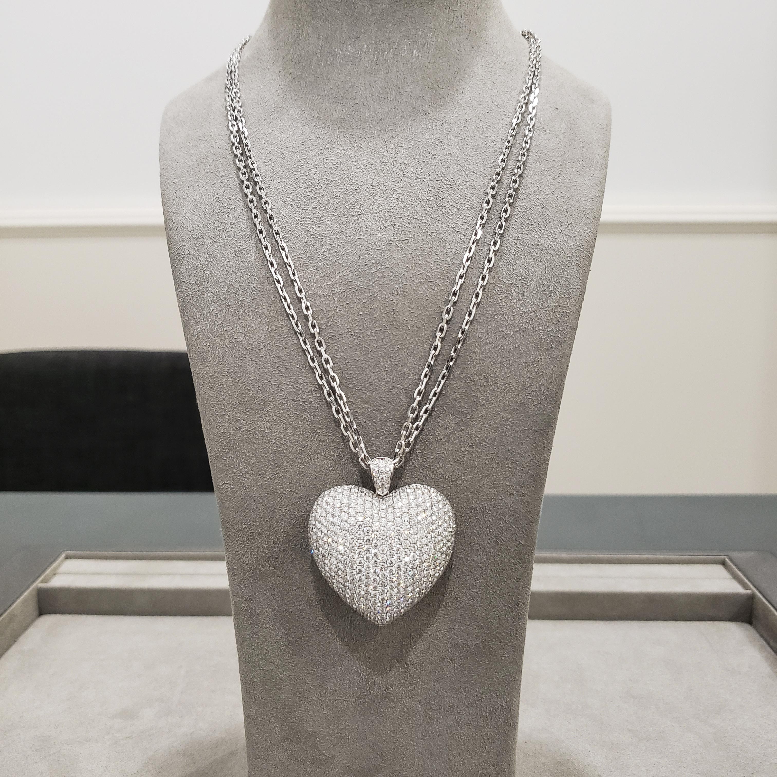 Showcasing an 18 karat white gold heart, encrusted with round brilliant diamonds weighing 12.10 carats total. Attach to a diamond encrusted bale. Suspended on two 20 inch white gold chain. 

