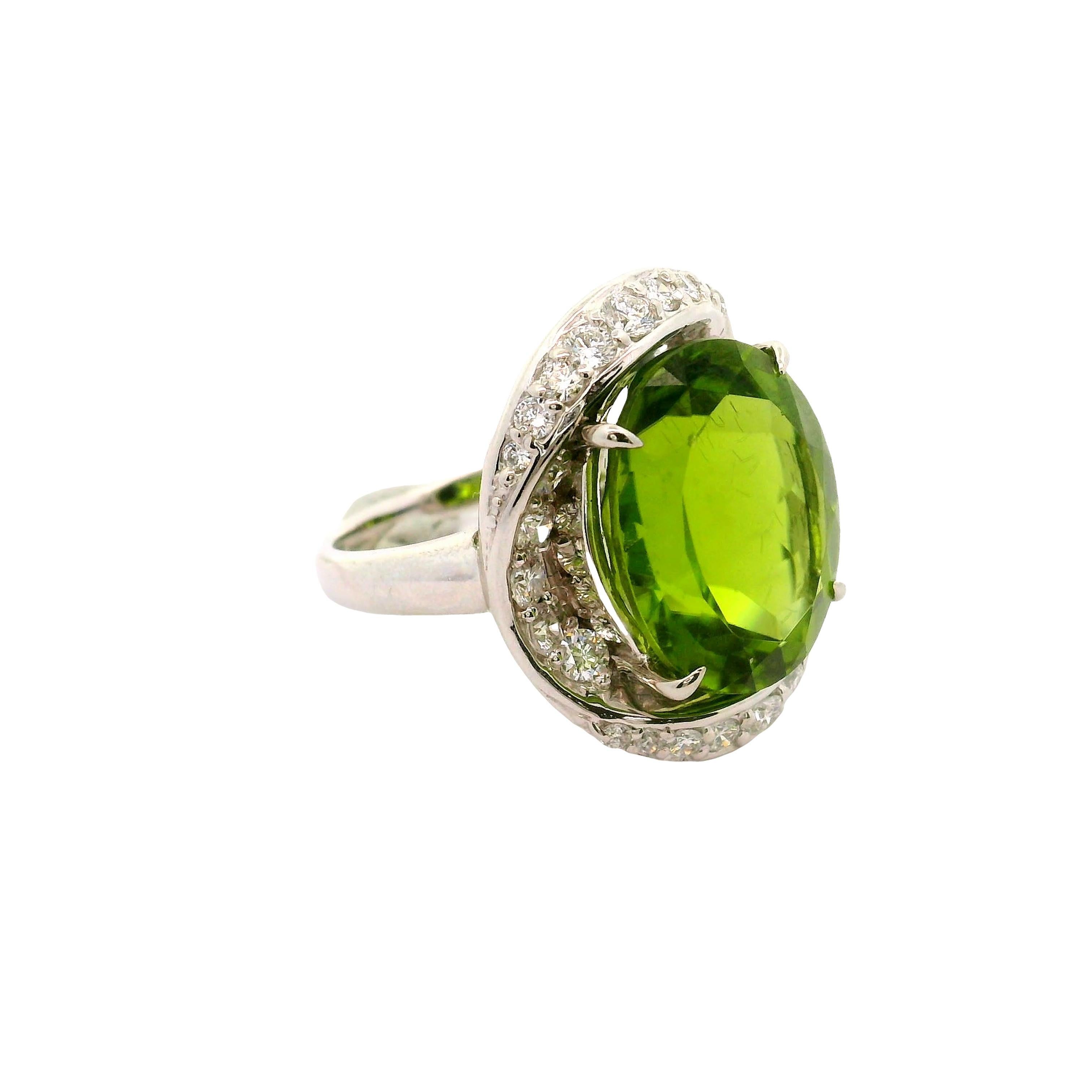 Un magnifique péridot pesant 12,12 carats occupe le devant de la scène dans cette bague en platine. Il présente une élégante taille ovale d'un vert éclatant. Autour du péridot, des diamants de taille ronde, totalisant 0,85 carats, offrent un