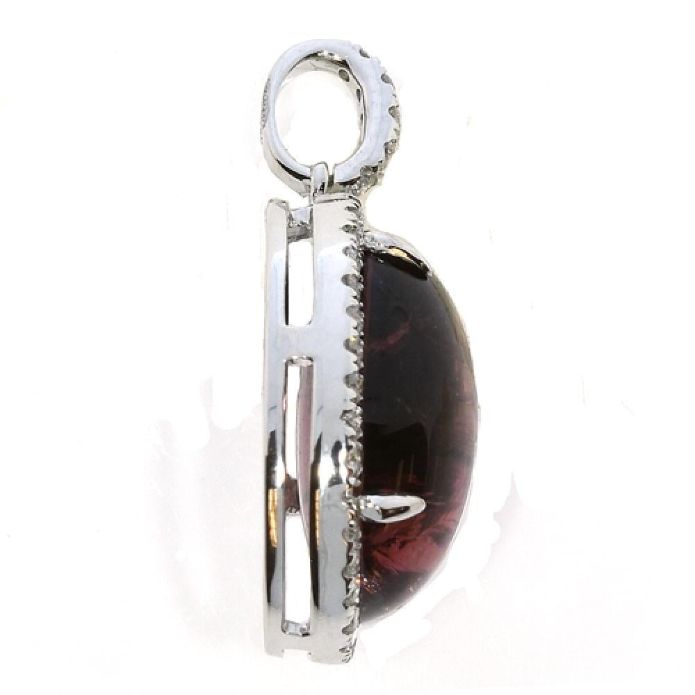 The 12.12 Carat Rhodolite Garnet and White Diamond Oval Pendant Necklace feature a magnificent 11.76 carat rhodolite gemstone. Surrounding the center stone there are round white diamonds that also follow up the clasp of the pendant. This stunning