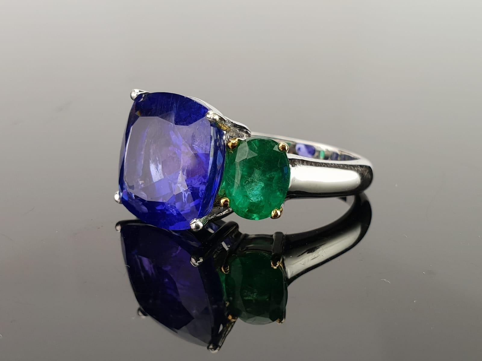 A unique cocktail and three-stone ring, with a beautiful, transparent Tanzanite centre stone, and lustrous Zambian Emerald side stones set in 18K White Gold. Certificate can be provided upon request. 

Centre Stone Details:  
Stone: Tanzanite
Cut: